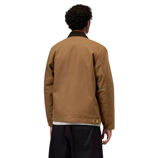 Casaco Carhartt WIP Detroit em Hamilton Brown/Tobacco Rigid, vista de costas a três quartos no modelo, mostrando a gola escura, as costas lisas e as presilhas de ajuste com molas na bainha.