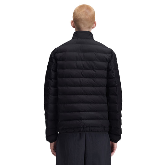 Casaco acolchoado para homem Fred Perry Insulated Jacket em Black — modelo masculino de costas, corpo inteiro, nylon reciclado preto, gola alta, enchimento acolchoado horizontal bem visível, mangas acolchoadas, barra elástica, etiqueta branca visível na barra lateral, calças azul escuro, fundo branco.