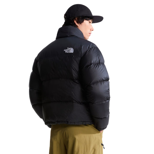 Casaco The North Face 1996 Retro Nuptse preto em modelo de costas a três quartos, mostrando os painéis acolchoados e o logótipo branco no ombro direito.