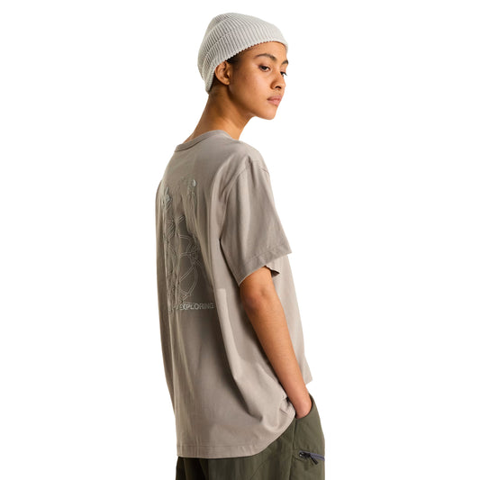T-shirt The North Face NSE Slopes Relaxed em stone slab — modelo de perfil traseiro, corpo inteiro, gráfico NSE Slopes parcialmente visível, gorro canelado cinzento claro, calças cargo verde military, fundo branco.