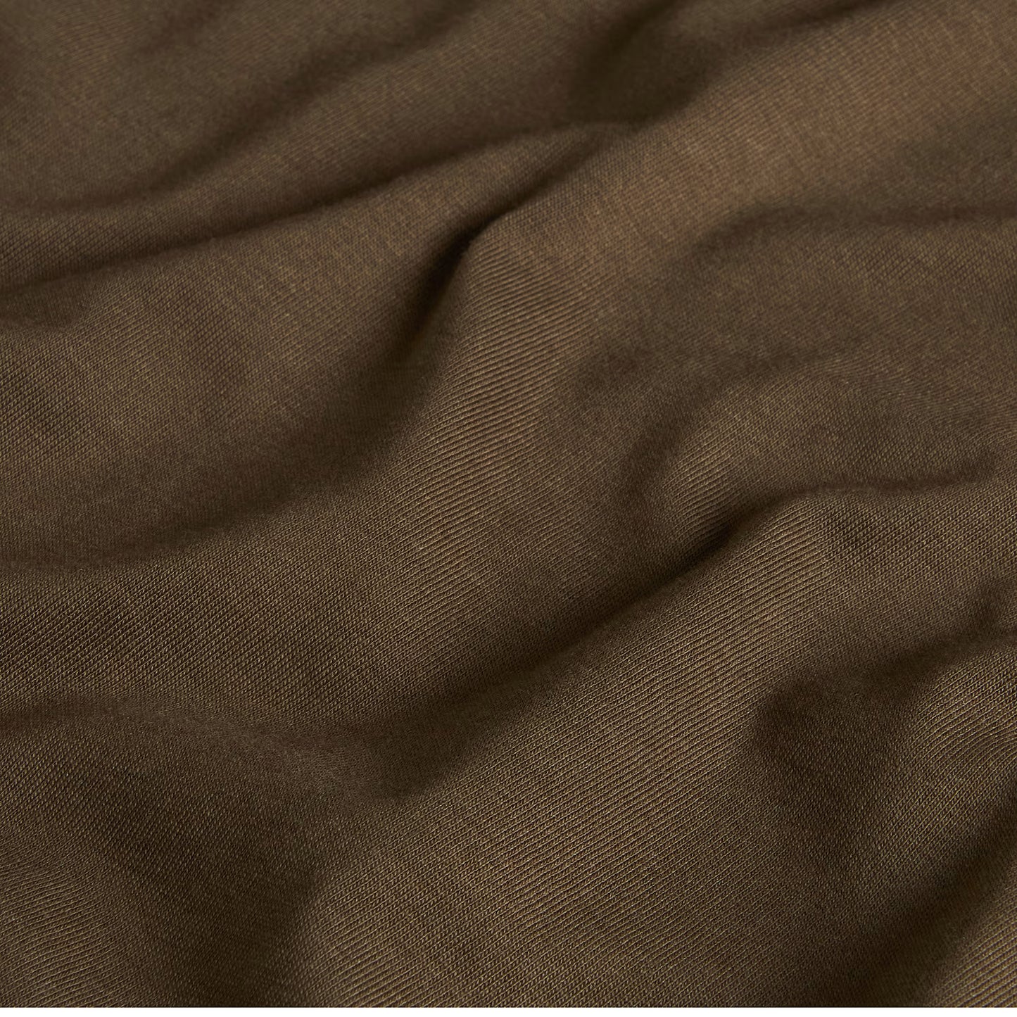 T-Shirt The North Face Yosemite Oak Box NSE Regular em New Taupe Green — detalhe do tecido jersey em New Taupe Green, textura de malha 165 g/m² com dobras suaves visíveis em close-up, fundo escuro.