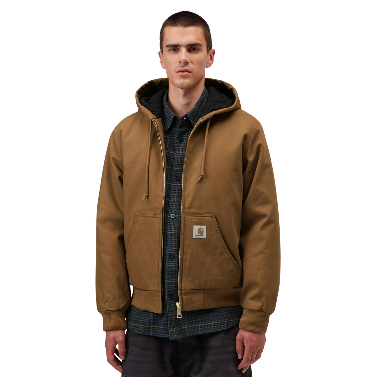 Casaco com carapuço Carhartt WIP Active em Hamilton Brown, vista frontal em plano médio no modelo, usado aberto sobre uma camisa escura de padrão xadrez, com fecho metálico, cordões e etiqueta quadrada no bolso.