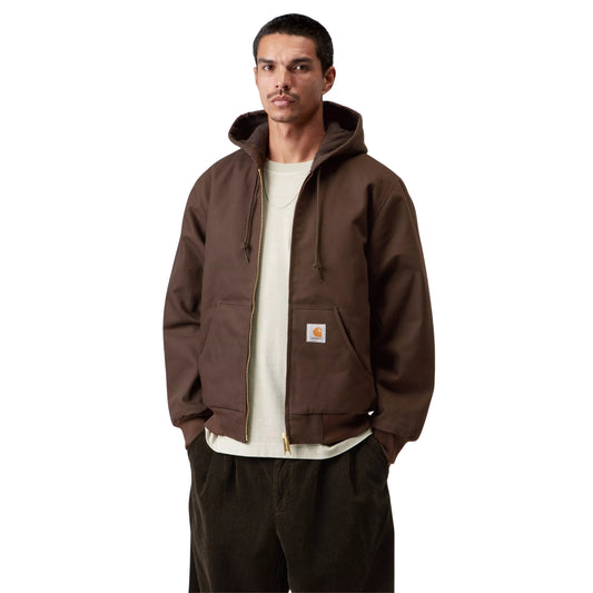 Casaco com carapuço Carhartt WIP Active em Tobacco Rigid, vista frontal em plano médio no modelo, usado aberto sobre uma t-shirt clara, com cordões, fecho metálico e etiqueta quadrada no bolso.