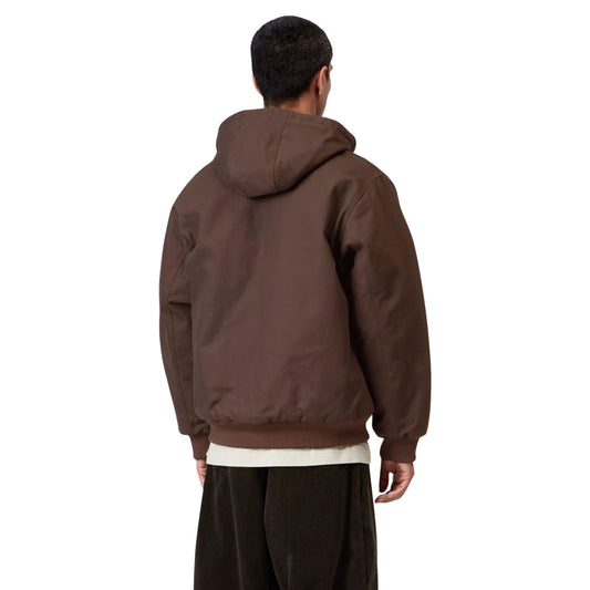 Casaco com carapuço Carhartt WIP Active em Tobacco Rigid, vista de costas a três quartos no modelo, mostrando o carapuço descido, as costas lisas e os punhos e bainha canelados.