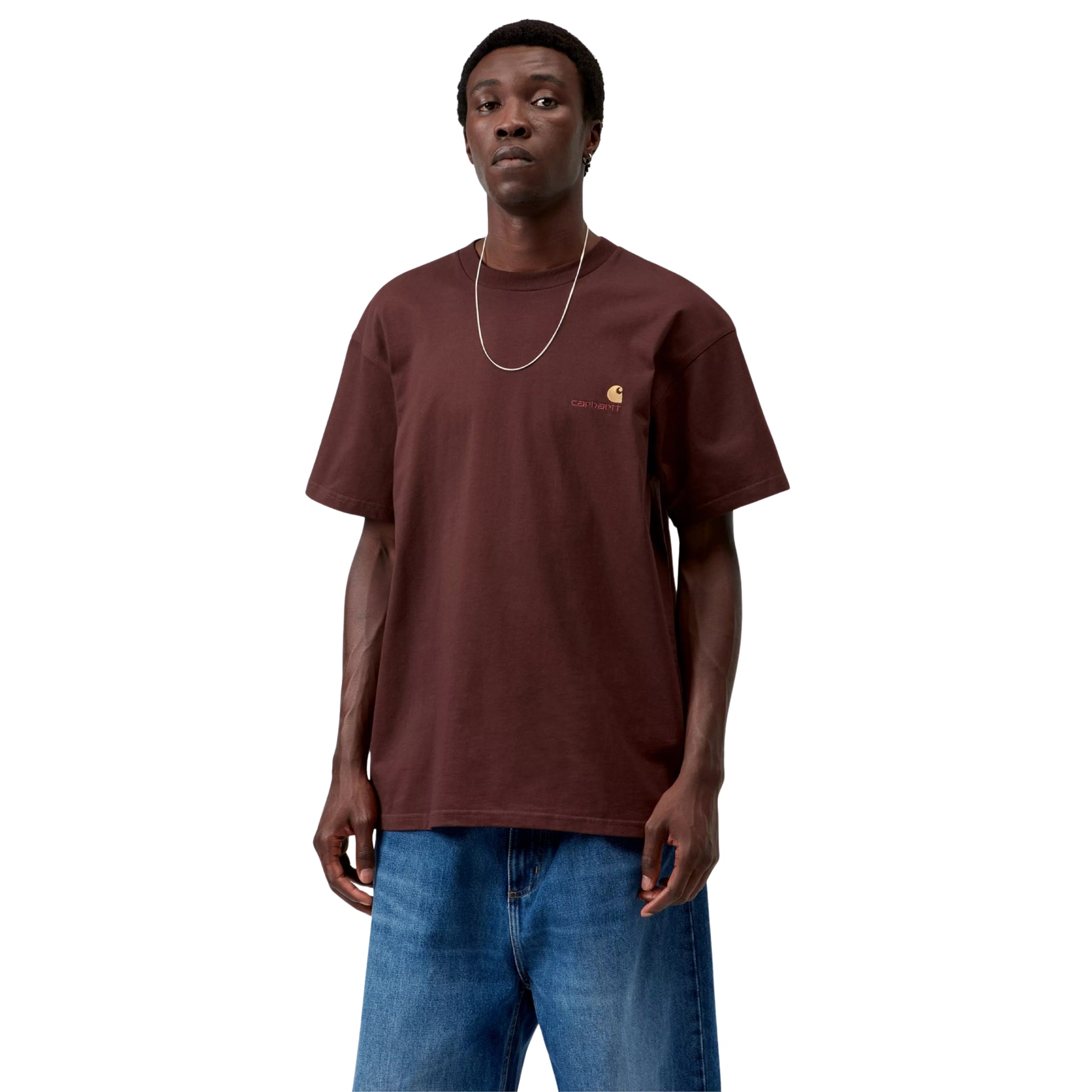 T-shirt Carhartt WIP American Script em Amarone — modelo masculino de frente, meio corpo, corrente fina dourada ao pescoço, logótipo American Script bordado no peito esquerdo com "C" dourado e texto "carhartt." em Amarone, decote redondo, manga curta, calças wide-leg denim azul médio, jersey de algodão bordeaux escuro Amarone, fundo branco.