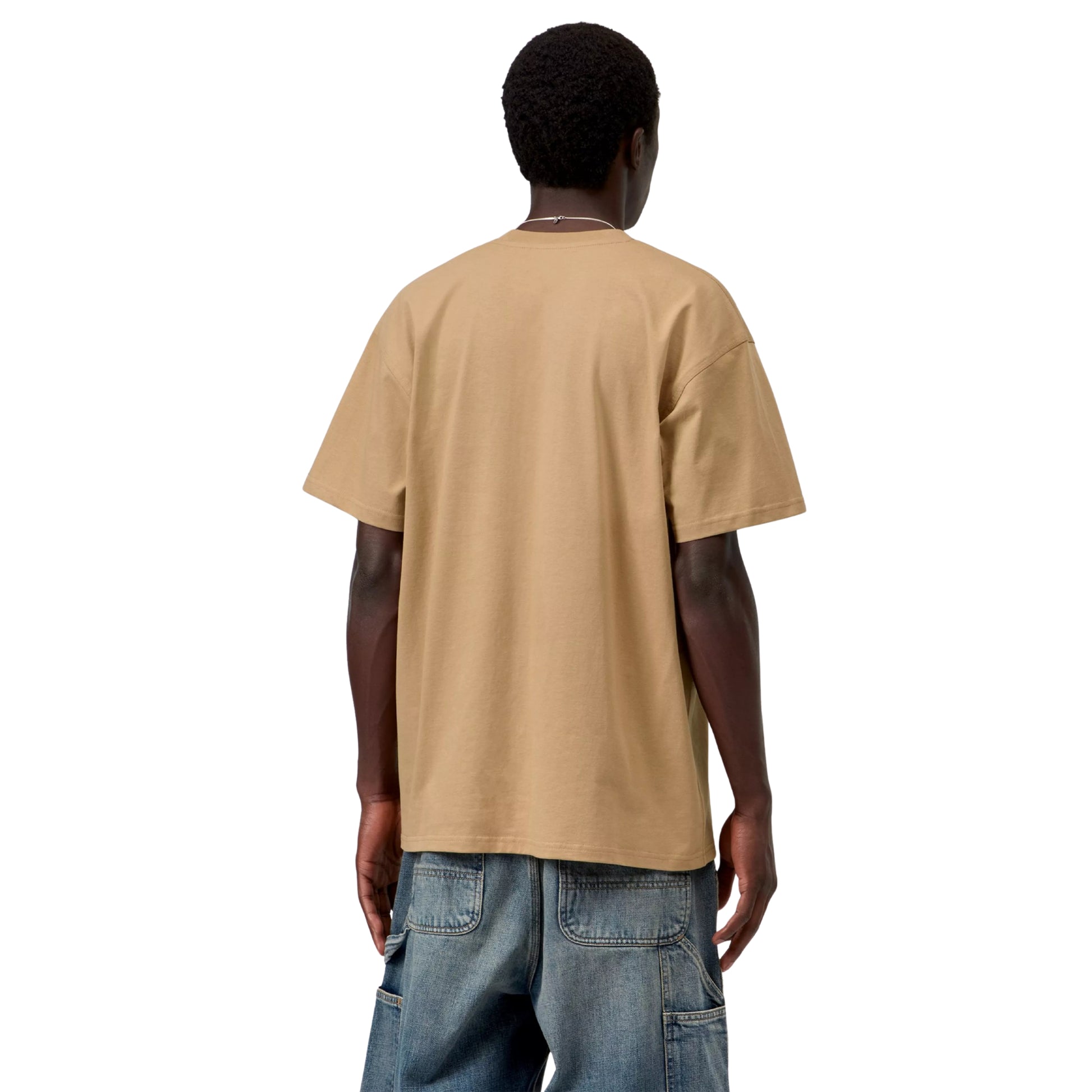 T-shirt Carhartt WIP S/S American Script em Dusty H Brown — modelo a usar a peça de costas, meio corpo, malha bege-camel arenoso com costas lisas, corte solto e bainha reta, calças Double Knee em ganga azul-médio desgastada, fundo branco.
