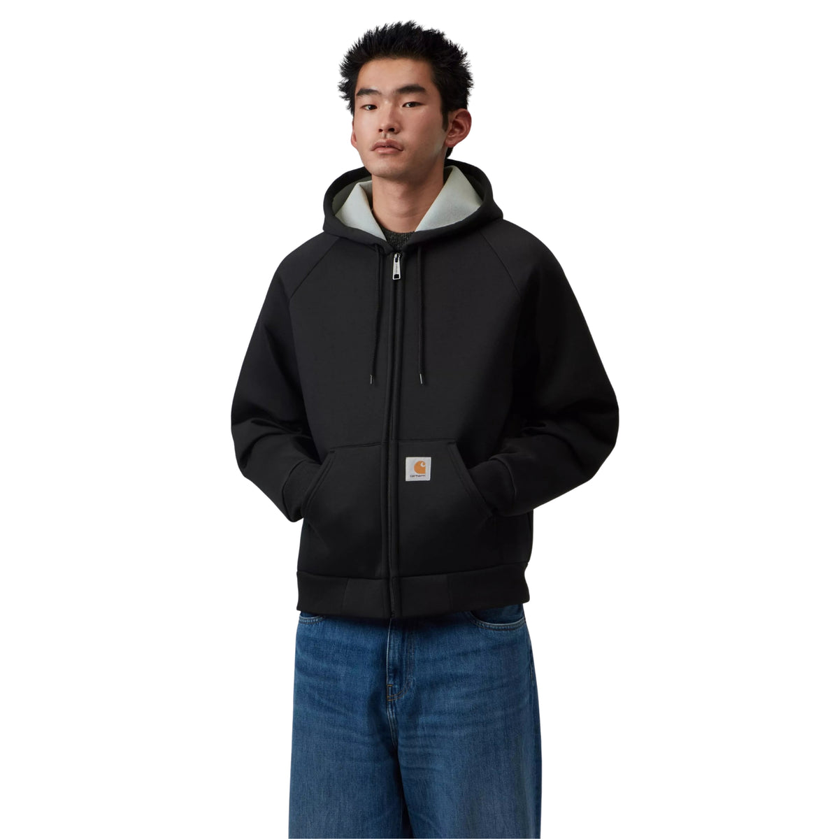 Casaco com carapuço Carhartt WIP Car-Lux em Black/Grey, vista frontal em plano médio no modelo, com fecho fechado, mãos nos bolsos, interior cinzento do carapuço e etiqueta quadrada visível.