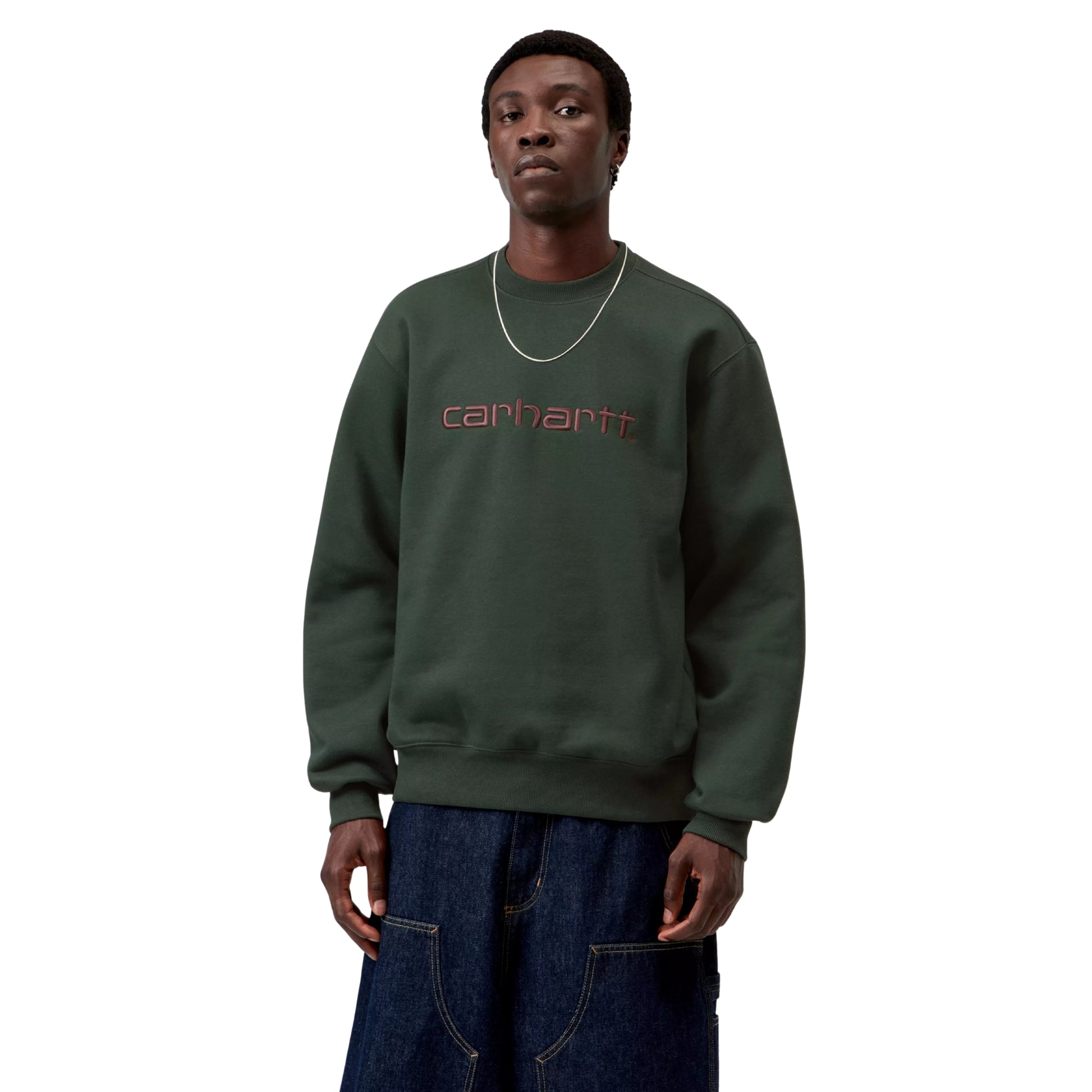 Sweatshirt Carhartt WIP Carhartt Sweat em Dark Scarab — modelo masculino de frente, meio corpo, cabelo curto escuro, corrente fina dourada ao pescoço, logótipo Script "carhartt." bordado ao peito em Palisander (bordeaux escuro), decote redondo canelado, corte solto com ombros descaídos, calças cargo wide-leg denim azul-escuro Carhartt WIP, malha escovada verde Dark Scarab, fundo branco.
