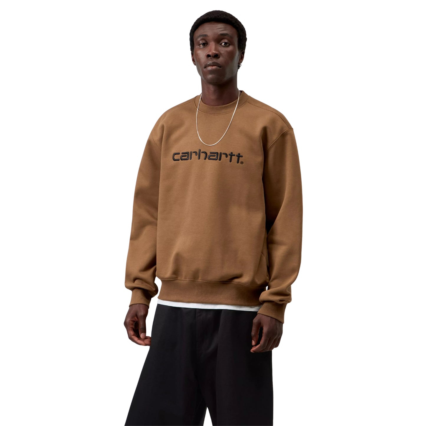 Sweatshirt Carhartt WIP Carhartt Sweat em WIP H Brown / Black — modelo masculino de frente, meio corpo, corrente fina prateada ao pescoço, logótipo Script "carhartt.®" bordado em Black no peito, decote redondo, corte solto e punhos canelados, calças largas pretas, malha escovada WIP H Brown, fundo branco.