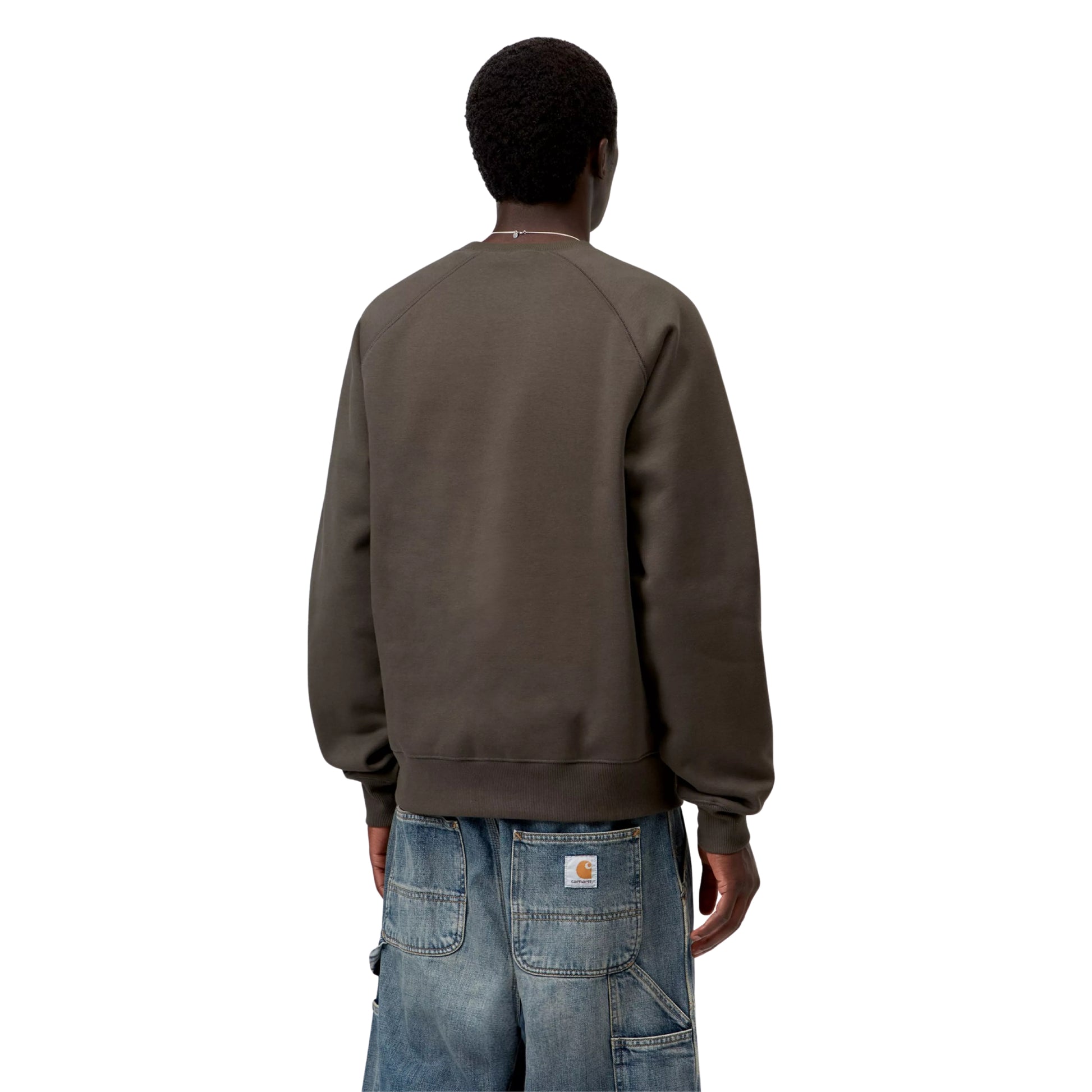 Sweat para homem Carhartt WIP Chase em Shungite / Gold — vista traseira com modelo, meio corpo, mangas raglan e decote redondo visíveis, combinado com calças de ganga largas.