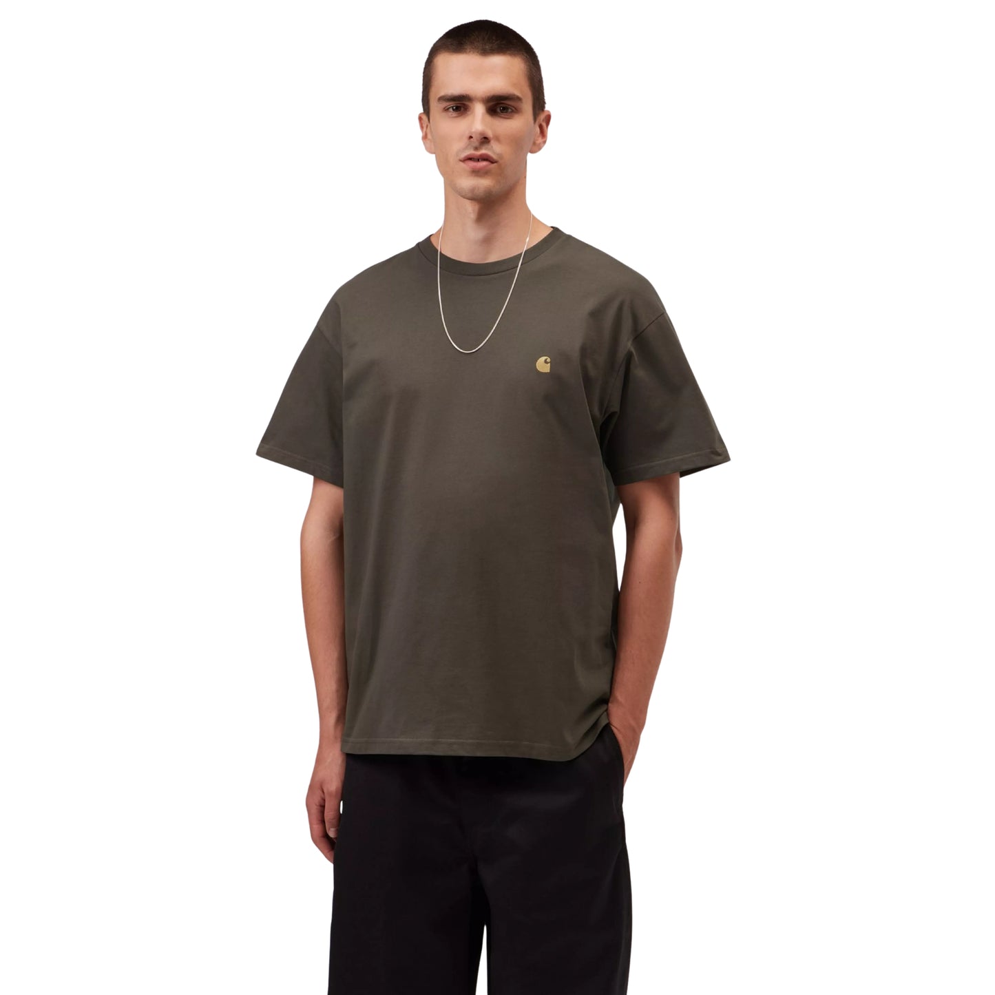 T-shirt manga curta Carhartt WIP S/S Chase em Shungite / Gold — vista frontal com modelo, meio corpo, logo "C" dourado bordado no peito esquerdo, combinado com calças largas pretas Carhartt WIP e corrente dourada.