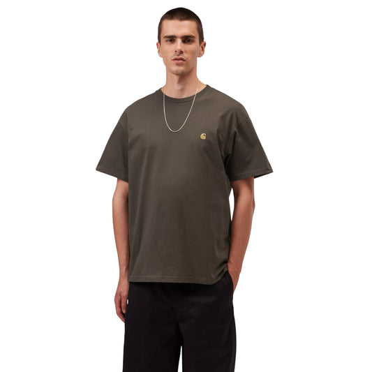 T-shirt manga curta Carhartt WIP S/S Chase em Shungite / Gold — vista frontal com modelo, meio corpo, logo "C" dourado bordado no peito esquerdo, combinado com calças largas pretas Carhartt WIP e corrente dourada.