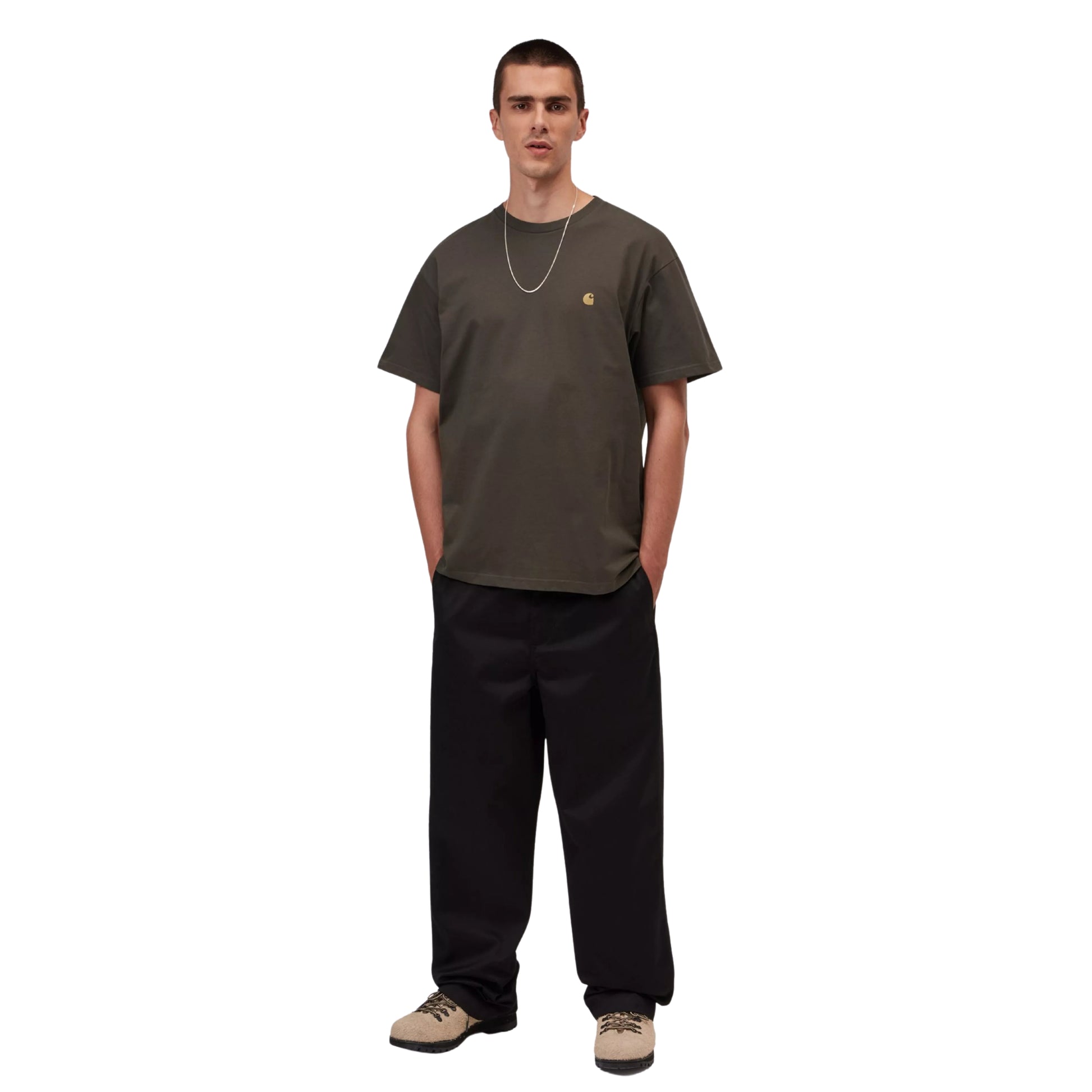 T-shirt manga curta Carhartt WIP S/S Chase em Shungite / Gold — look completo com modelo, corpo inteiro, corte loose visível, combinado com calças largas pretas Carhartt WIP e sapatilhas bege.