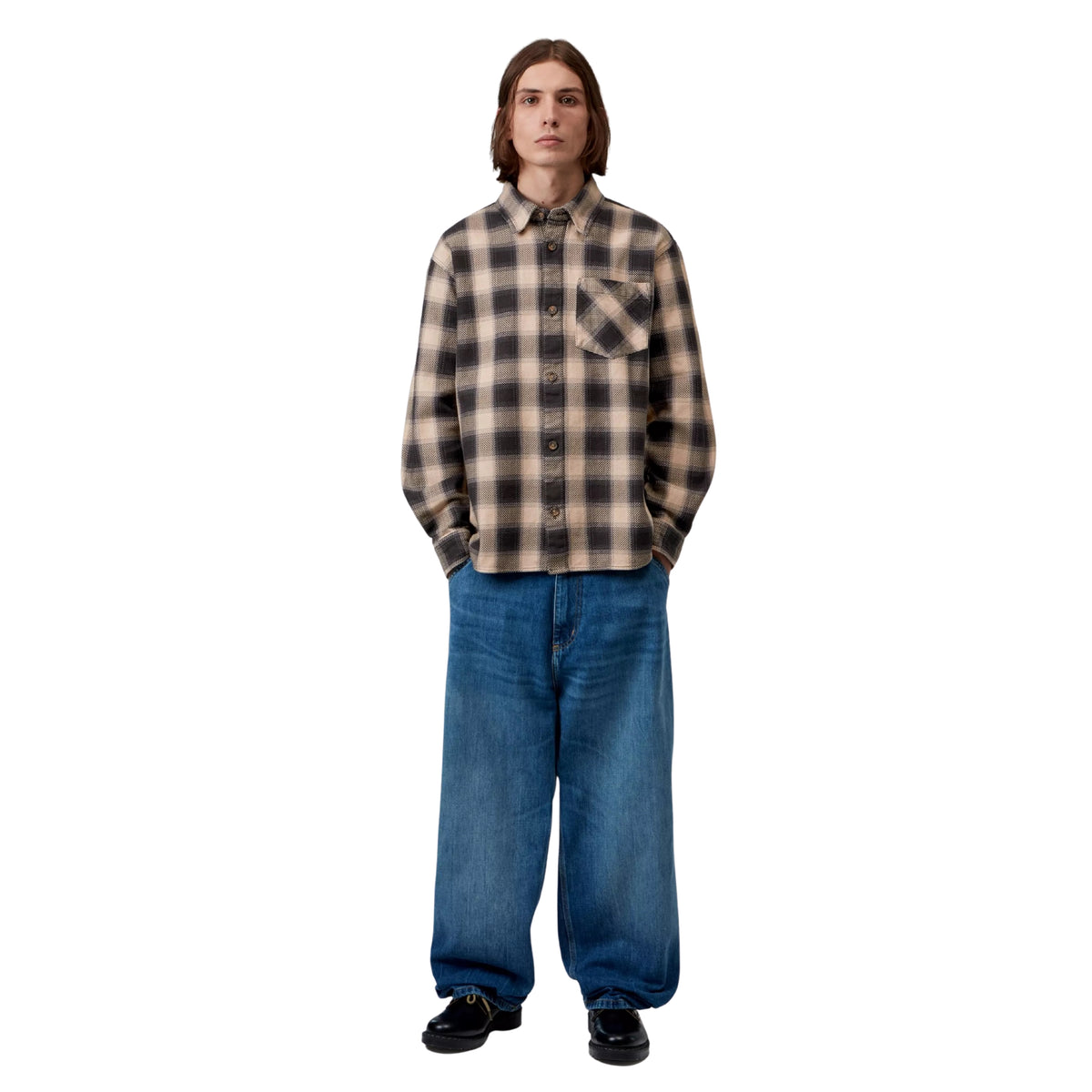 Camisa de manga comprida Carhartt WIP L/S Dayne em Dayne Check Shady Purple — modelo masculino de frente, corpo inteiro, camisa de xadrez grande escala em bege e roxo escuro, loose fit, calças largas de ganga azul, sapatos pretos, fundo branco.