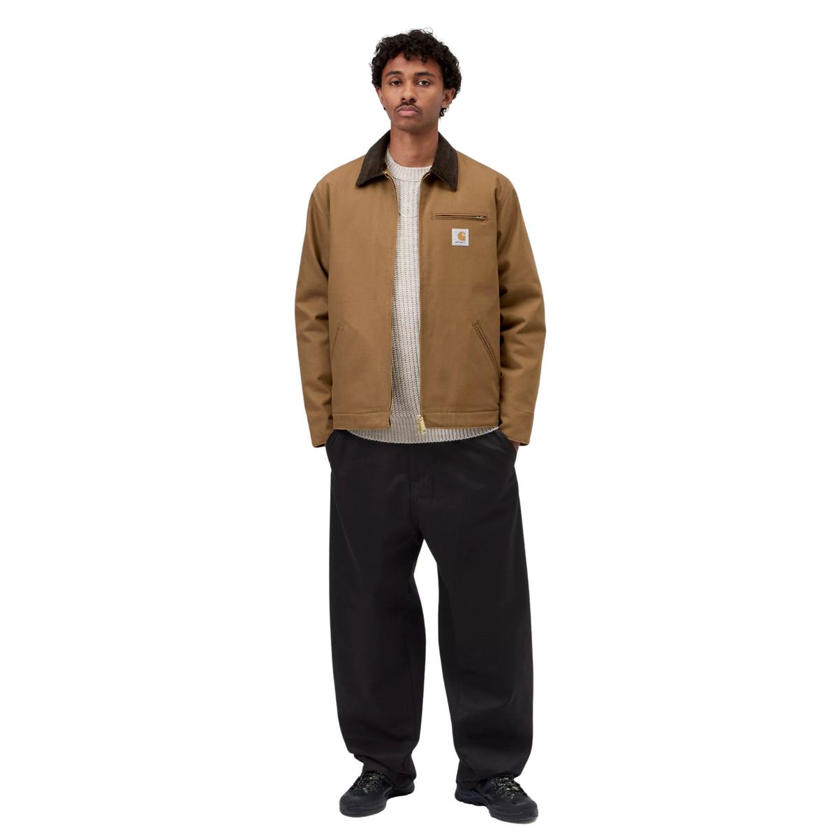 Casaco Carhartt WIP Detroit em Hamilton Brown/Tobacco Rigid, vista frontal de corpo inteiro no modelo, usado aberto sobre uma camisola de malha clara, com calças largas pretas e calçado escuro.