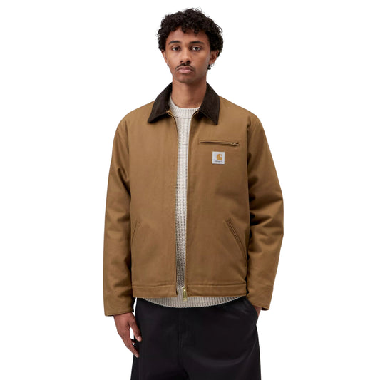Casaco Carhartt WIP Detroit em Hamilton Brown/Tobacco Rigid, vista frontal em plano médio no modelo, usado aberto sobre uma camisola de malha clara, com gola escura, bolso de peito com fecho e etiqueta quadrada.