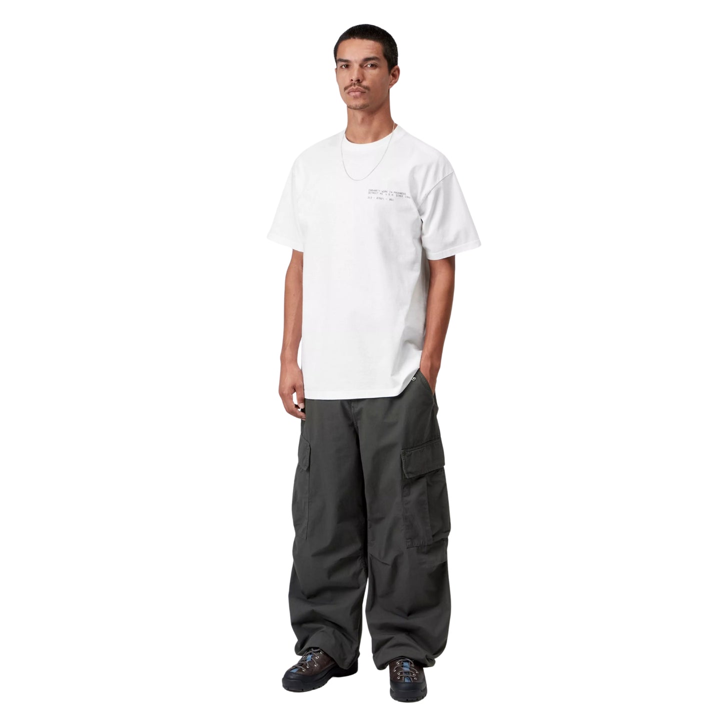 T-shirt Carhartt WIP S/S Feather Progress em White — modelo masculino de frente, corpo inteiro, cabelo curto escuro, bigode, calças cargo cinzento-escuro largas Carhartt WIP, sapatilhas de trail pretas, texto tipográfico discreto no peito esquerdo visível, corte solto com ombros descaídos, malha de algodão biológico branco, fundo branco.