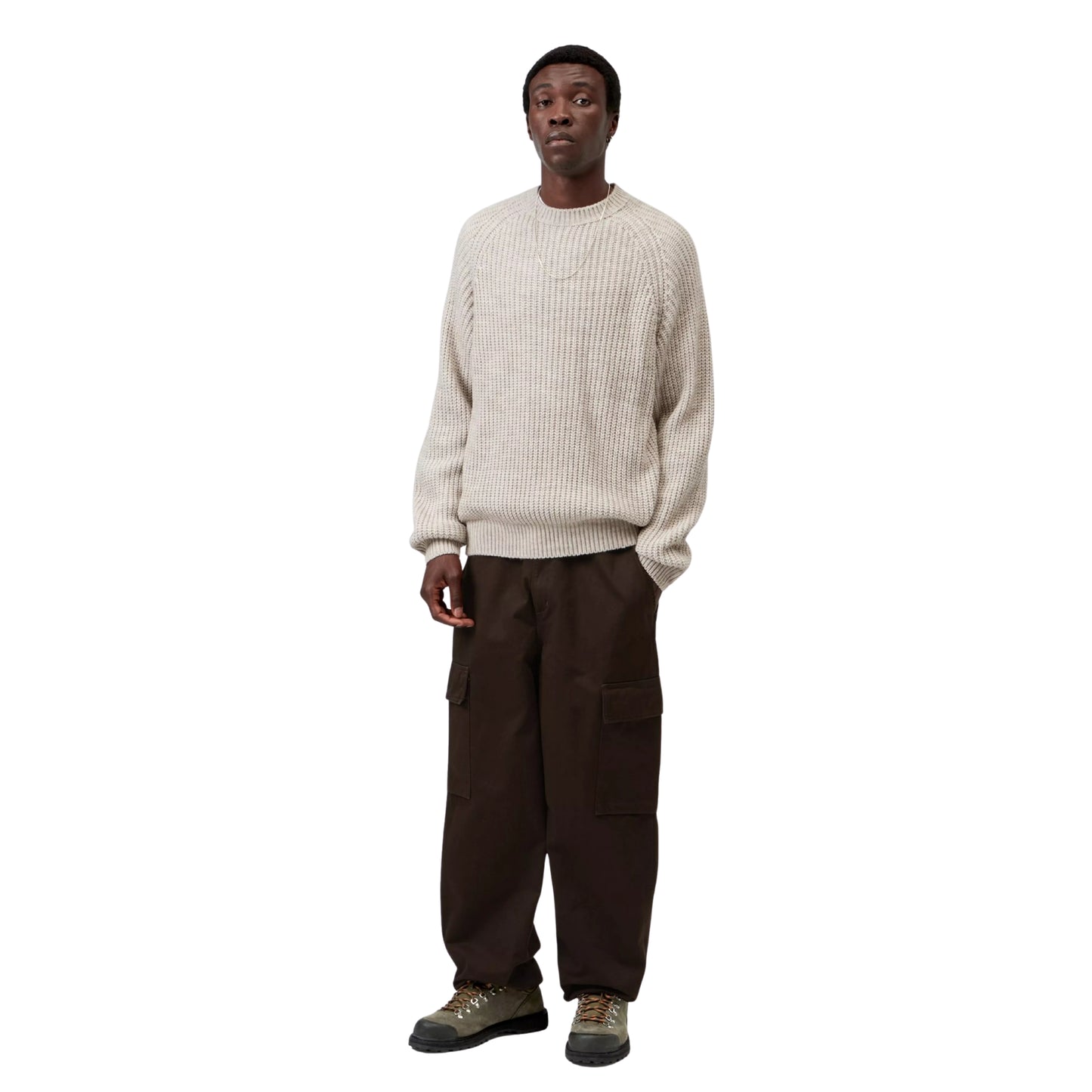 Camisola Carhartt WIP Firth Sweater em Fleur de Sel — modelo a usar a camisola de frente, corpo inteiro, malha bege-areia muito claro com textura canelada vertical e efeito melange, mangas raglan, decote redondo, etiqueta Square Label Carhartt WIP na bainha, calças cargo castanho-escuras e botas de caminhada cinzento-oliva, fundo branco.