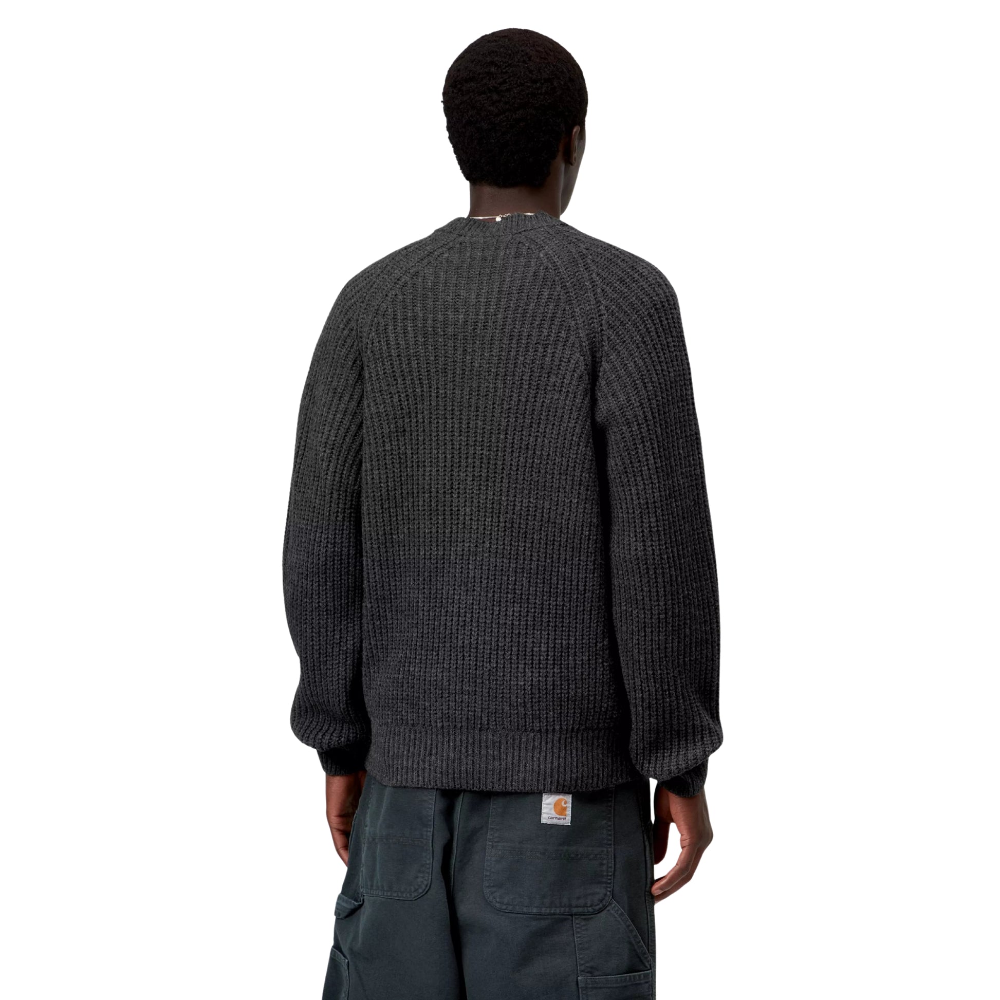 Camisola Carhartt WIP Firth Sweater em Soot — modelo a usar a camisola de costas, meio corpo, malha cinzento-chumbo escuro com textura canelada vertical, mangas raglan, decote redondo, punhos e bainha canelados, etiqueta Square Label Carhartt WIP na bainha traseira, fundo branco.