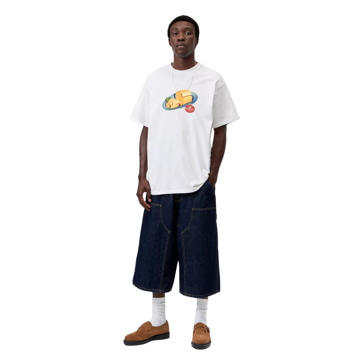T-shirt de manga curta Carhartt WIP S/S Fromage em Branco — modelo de corpo inteiro de frente, estampado gráfico Fromage no peito, calções de ganga azul-escuro, meias brancas e mocassins castanhos, fundo branco.