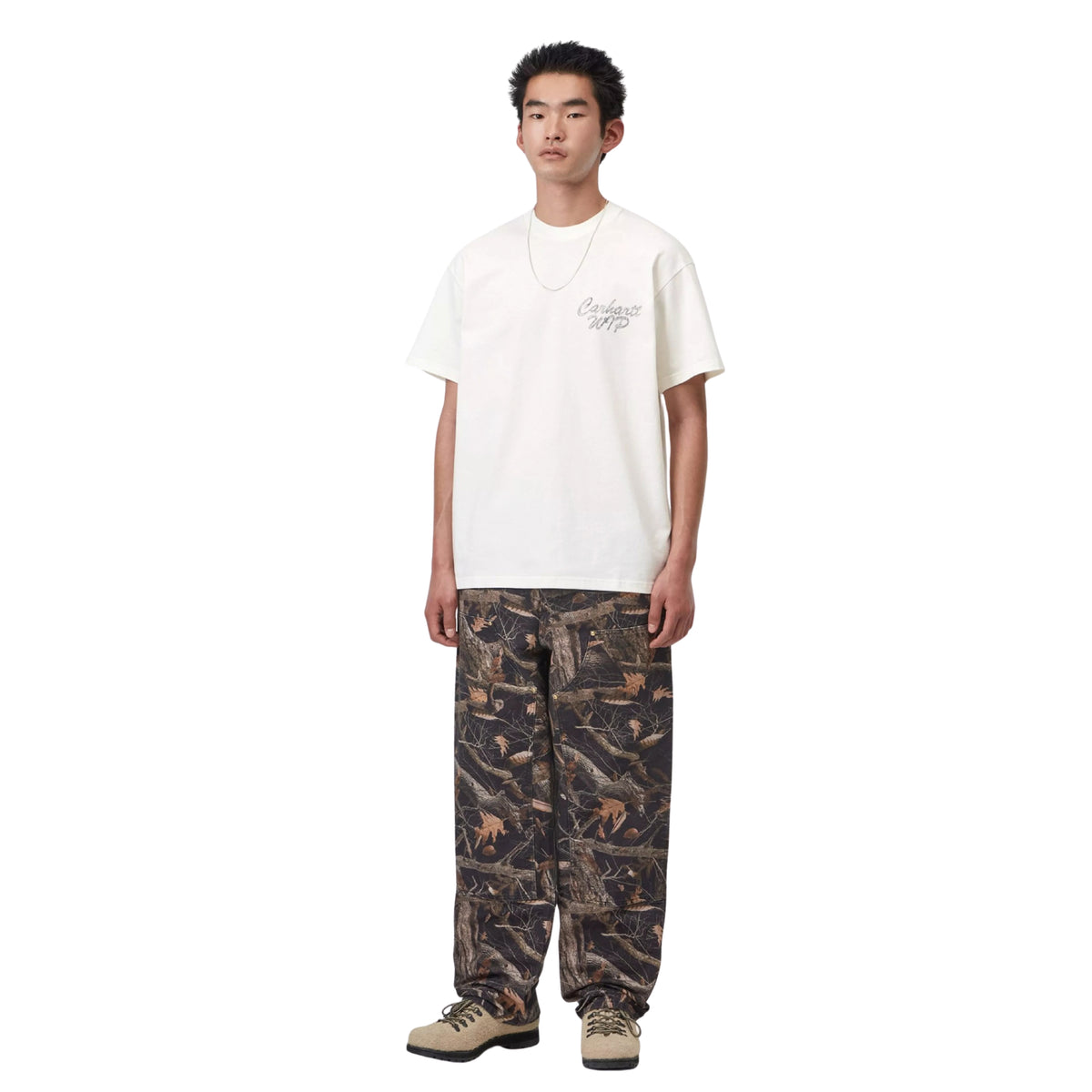 T-shirt de manga curta Carhartt WIP Hatching Script em Wax, vista frontal de corpo inteiro no modelo, combinada com calças largas de padrão camuflado e calçado bege.