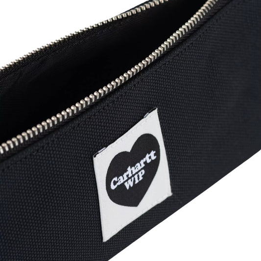 Estojo Carhartt WIP Heart Pencil Case em preto — detalhe da etiqueta Heart com logo Carhartt WIP e fecho de correr prateado aberto, textura da lona Dearborn visível.