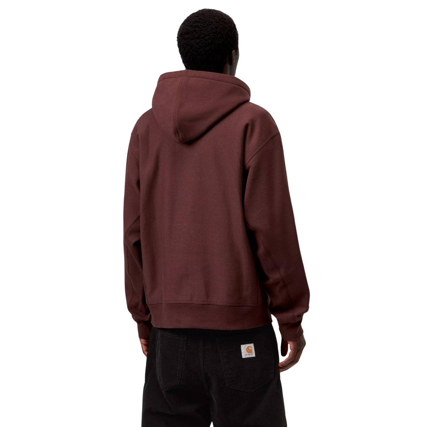 Hoodie Carhartt WIP Hooded American Script Sweat em Amarone — modelo a usar a peça de costas, meio corpo superior, capuz amplo com interior preto contrastante, malha bordô-vinho escuro, costas lisas, calças wide-leg pretas com Square Label Carhartt WIP bege visível, fundo branco.