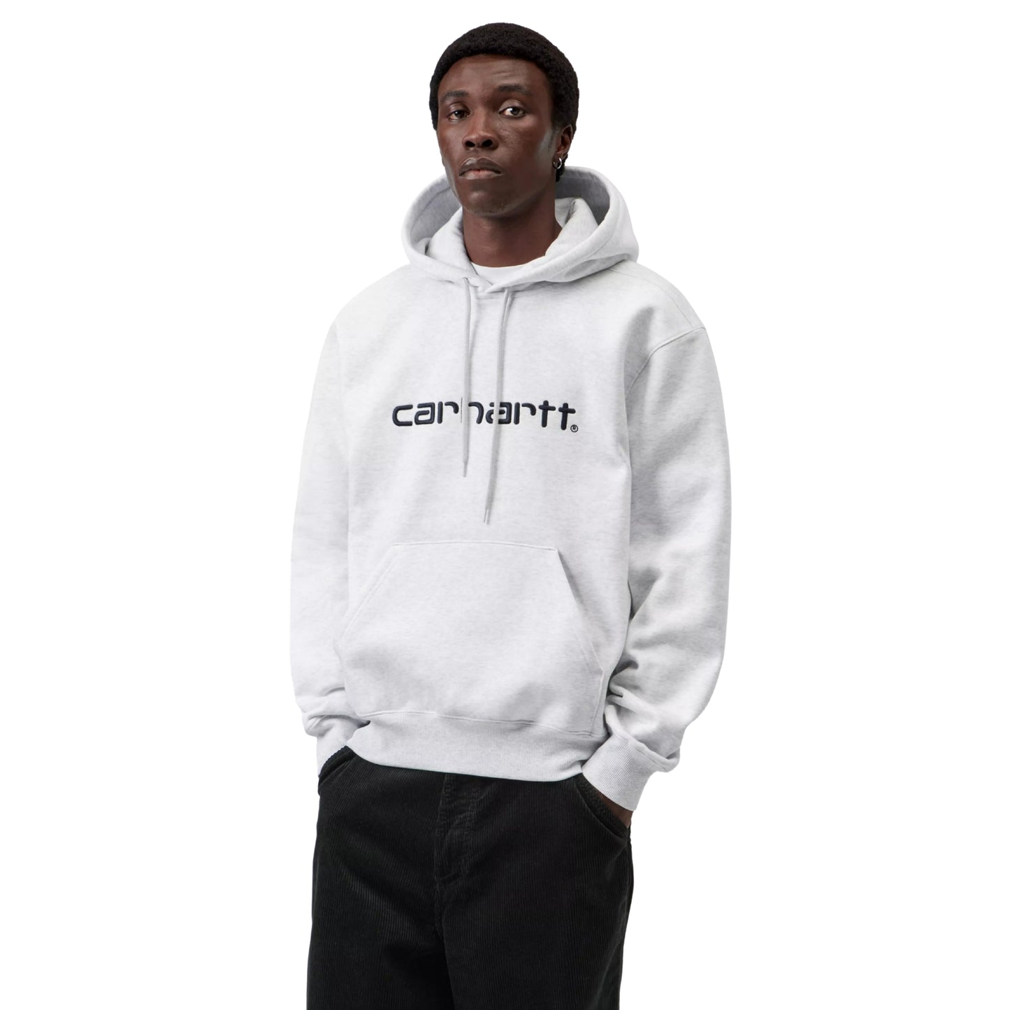 Hoodie Carhartt WIP Hooded Carhartt Sweat em Ash Heather — modelo masculino de frente, meio corpo, cabelo curto escuro, brinco pequeno na orelha direita, capuz levantado com interior cinzento Graphite visível, cordão de ajuste cinzento com ponteiras metálicas, logótipo Script "carhartt.®" bordado ao peito em Graphite, bolso canguru com mãos dentro, punhos canelados, calças wide-leg pretas Carhartt WIP, malha escovada cinzento mesclado Ash Heather, fundo branco.
