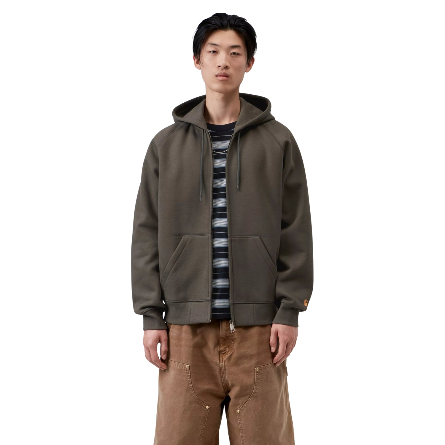 Casaco com carapuço Carhartt WIP Hooded Chase Jacket em Shungite / Gold — vista frontal com modelo, meio corpo, fecho aberto, logo "C" dourado na manga esquerda, combinado com t-shirt às riscas e calças cargo castanhas Carhartt WIP.