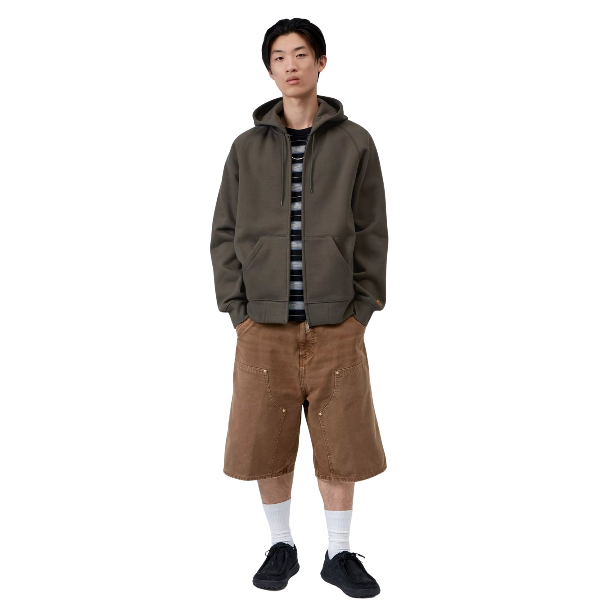 Casaco com carapuço Carhartt WIP Hooded Chase Jacket em Shungite / Gold — look completo com modelo, corpo inteiro, fecho fechado, mãos nos bolsos, combinado com calças cargo castanhas largas, meias brancas e sapatilhas pretas.