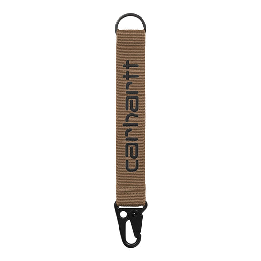 Porta-chaves Carhartt WIP Jaden Keyholder em WIP H Brown / Black — vista frontal, tira de rede de poliéster canelada castanho-quente com letras "carhartt" bordadas em preto em relevo ao centro, argola D-ring preta no topo, mosquetão tático preto na parte inferior, fundo branco.