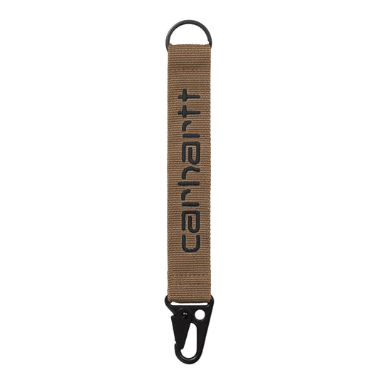 Porta-chaves Carhartt WIP Jaden Keyholder em WIP H Brown / Black — vista traseira, tira de rede de poliéster canelada castanho-quente com letras "carhartt" bordadas em preto em relevo ao centro (texto espelhado), argola D-ring preta no topo, mosquetão tático preto na parte inferior, fundo branco.