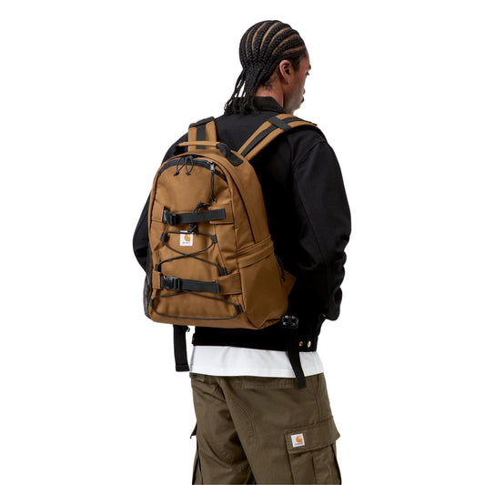 Mochila unissexo Carhartt WIP Kickflip em Hamilton Brown. Foto da mochila nas costas de modelo.
