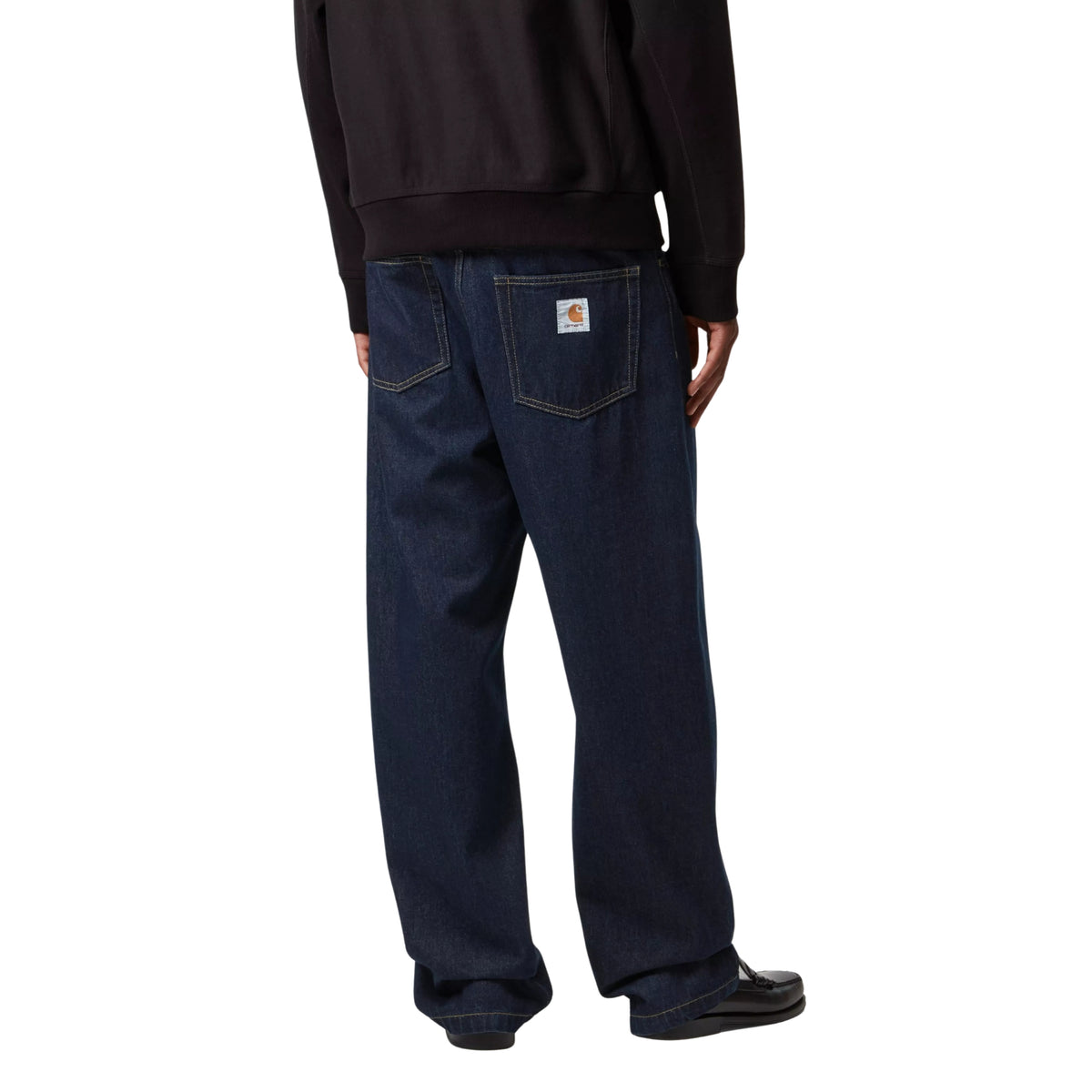 Calças de ganga Carhartt WIP Landon em azul Rinsed, vestidas por modelo de costas a três quartos, com bolsos traseiros e etiqueta quadrada no bolso direito.