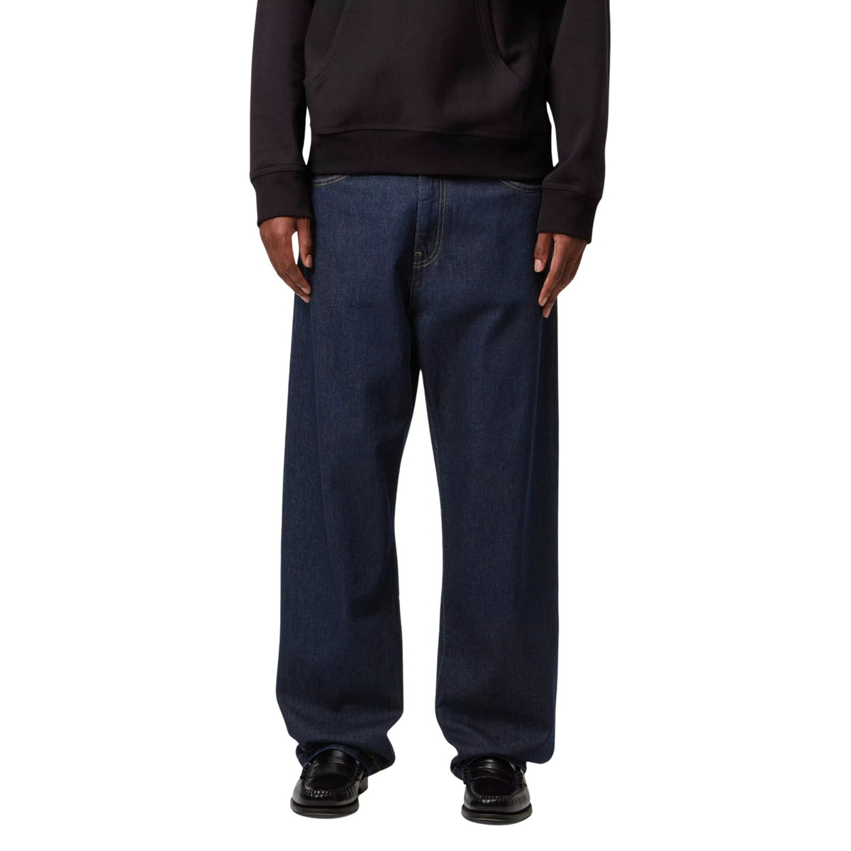 Calças de ganga Carhartt WIP Landon em azul Rinsed, vista frontal em modelo, com pernas largas e bainhas assentes sobre sapatos pretos.