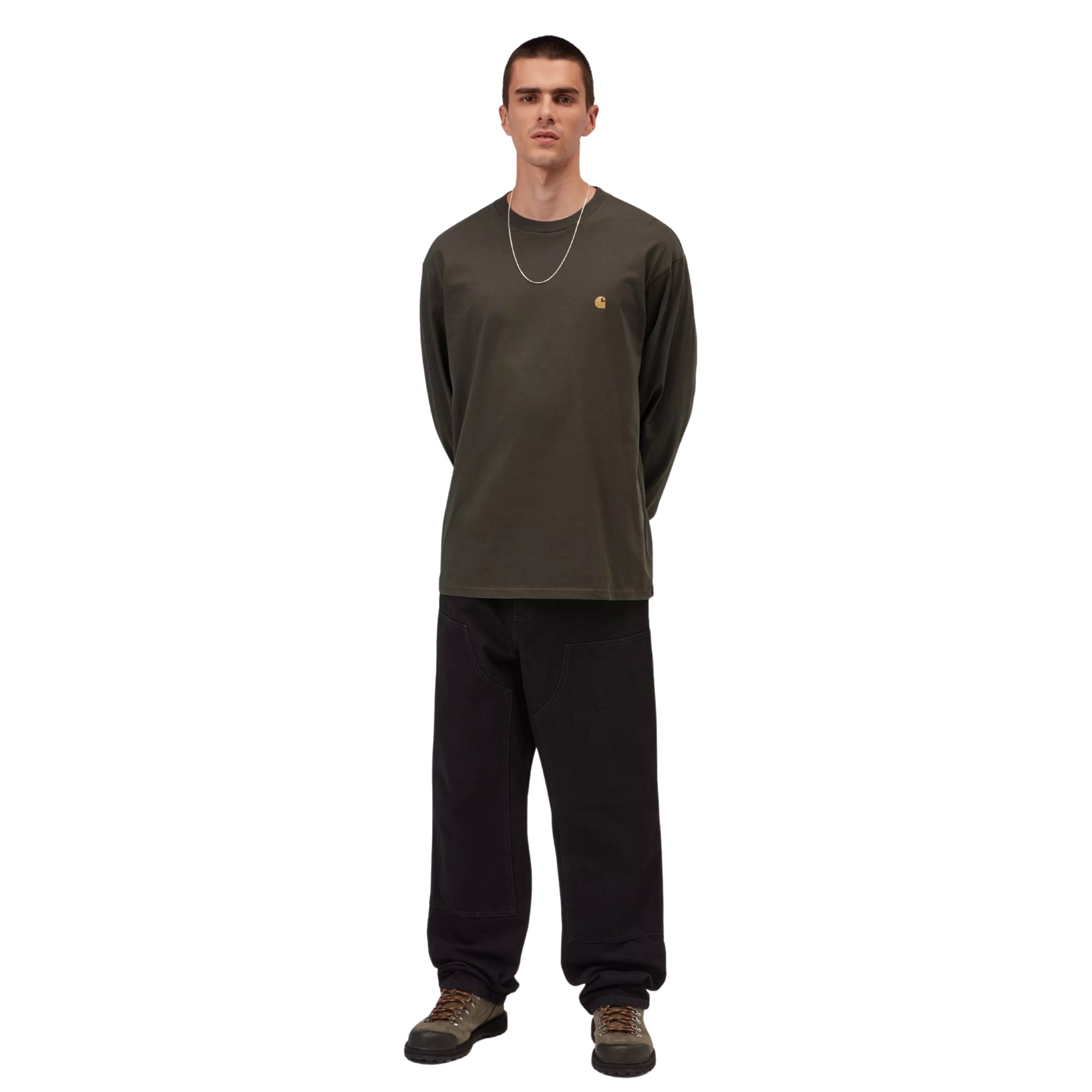 T-shirt manga comprida Carhartt WIP L/S Chase em Shungite / Gold — look completo com modelo, corpo inteiro, corte loose visível, combinado com calças largas pretas e botas de caminhada castanhas.