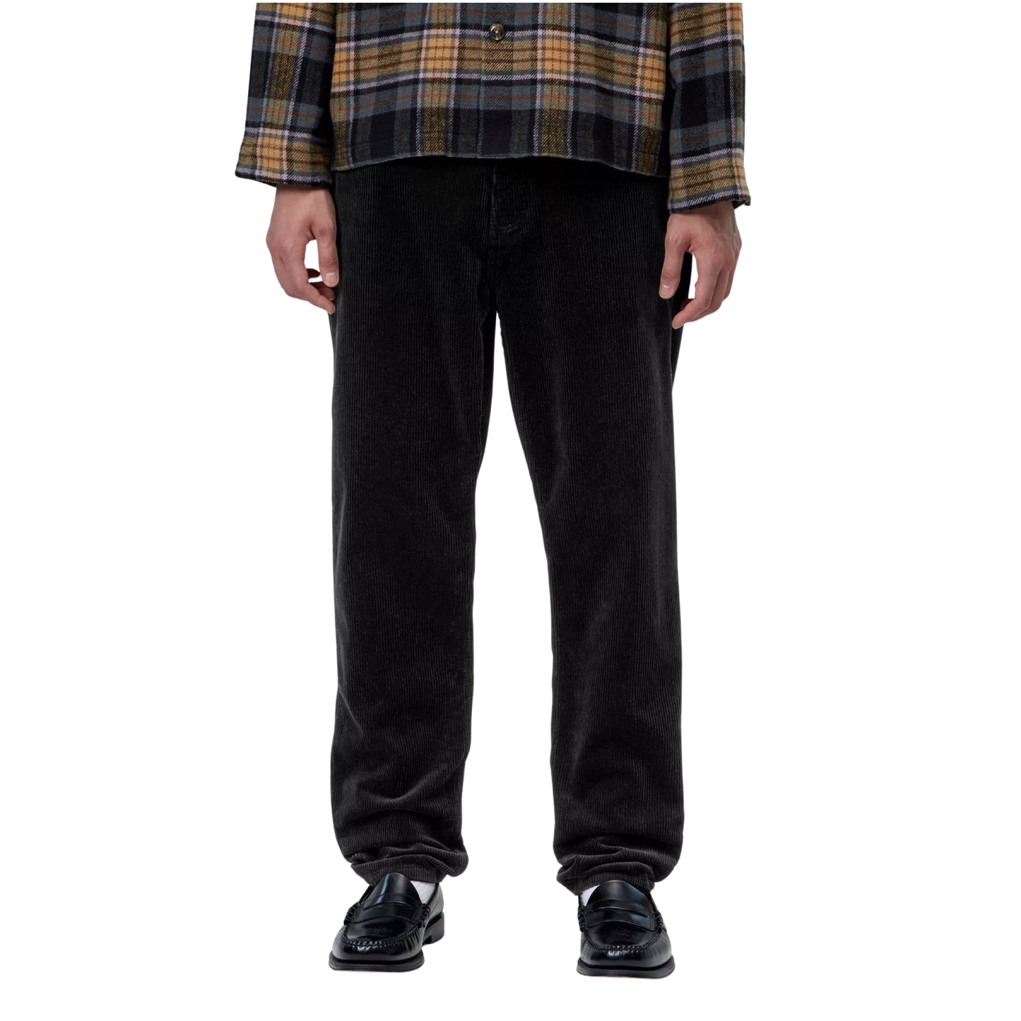 Calças Carhartt WIP Newel Pant em Black — modelo masculino de frente, meio corpo inferior, casaco xadrez oversized castanho e cinzento Carhartt WIP, calças em bombazina Coventry preta com corte relaxado afunilado e cintura regular, bolsos frontais visíveis, loafers pretos, fundo branco.