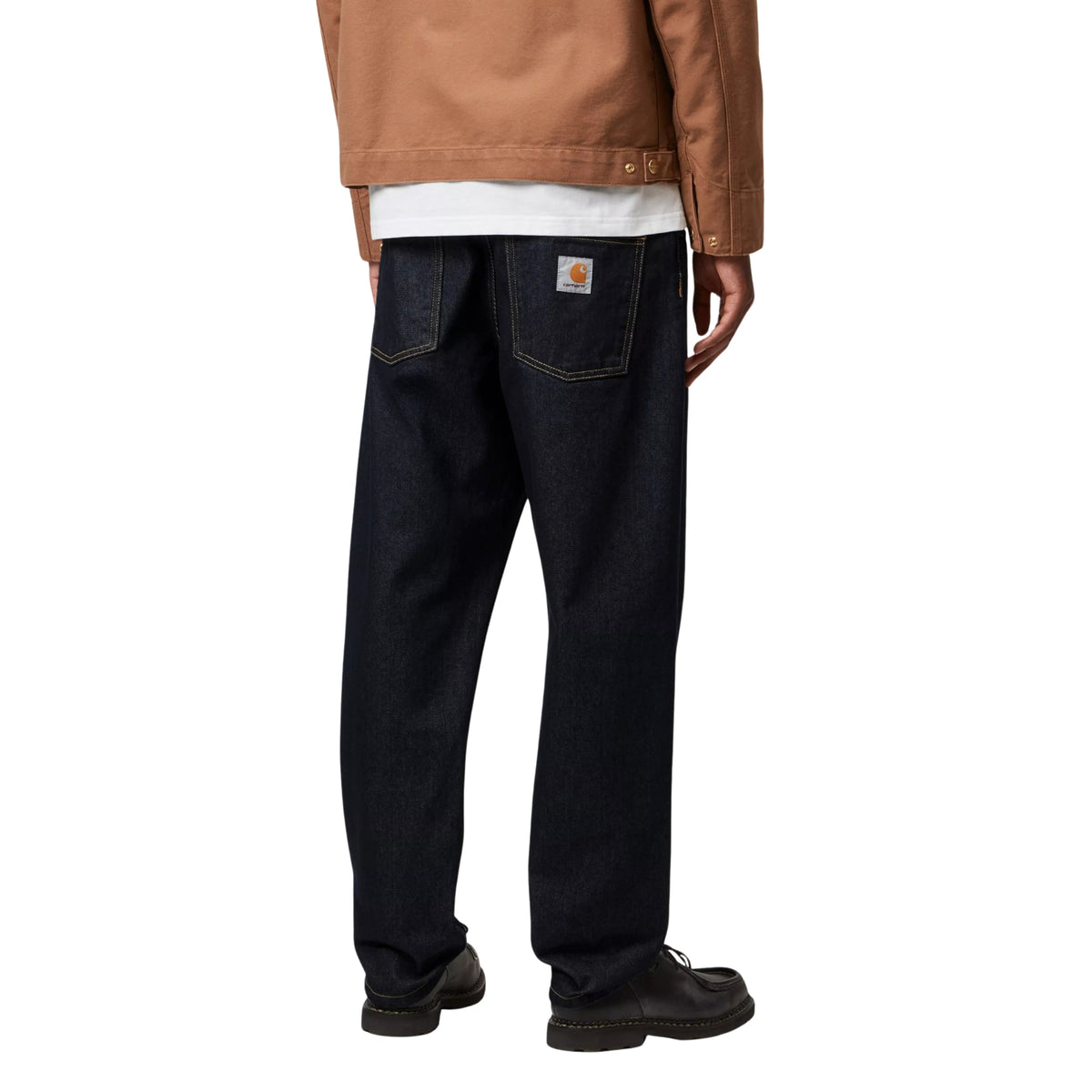 Calças de ganga Carhartt WIP Newel em azul One Wash, vestidas por modelo de costas, com bolsos traseiros e etiqueta quadrada no bolso direito.
