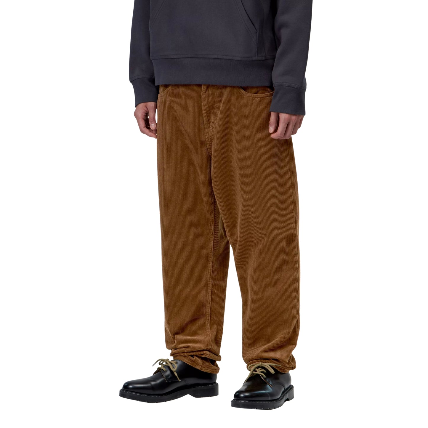 Calças Carhartt WIP Newel Pant em Hamilton Brown Rinsed — modelo masculino de frente, meio corpo inferior, sweatshirt com capuz cinzento-azulado, calças em bombazina Coventry castanha Hamilton Brown rinsed, corte relaxado afunilado com cintura regular e bolsos frontais visíveis, sapatos pretos de sola plana, fundo branco.