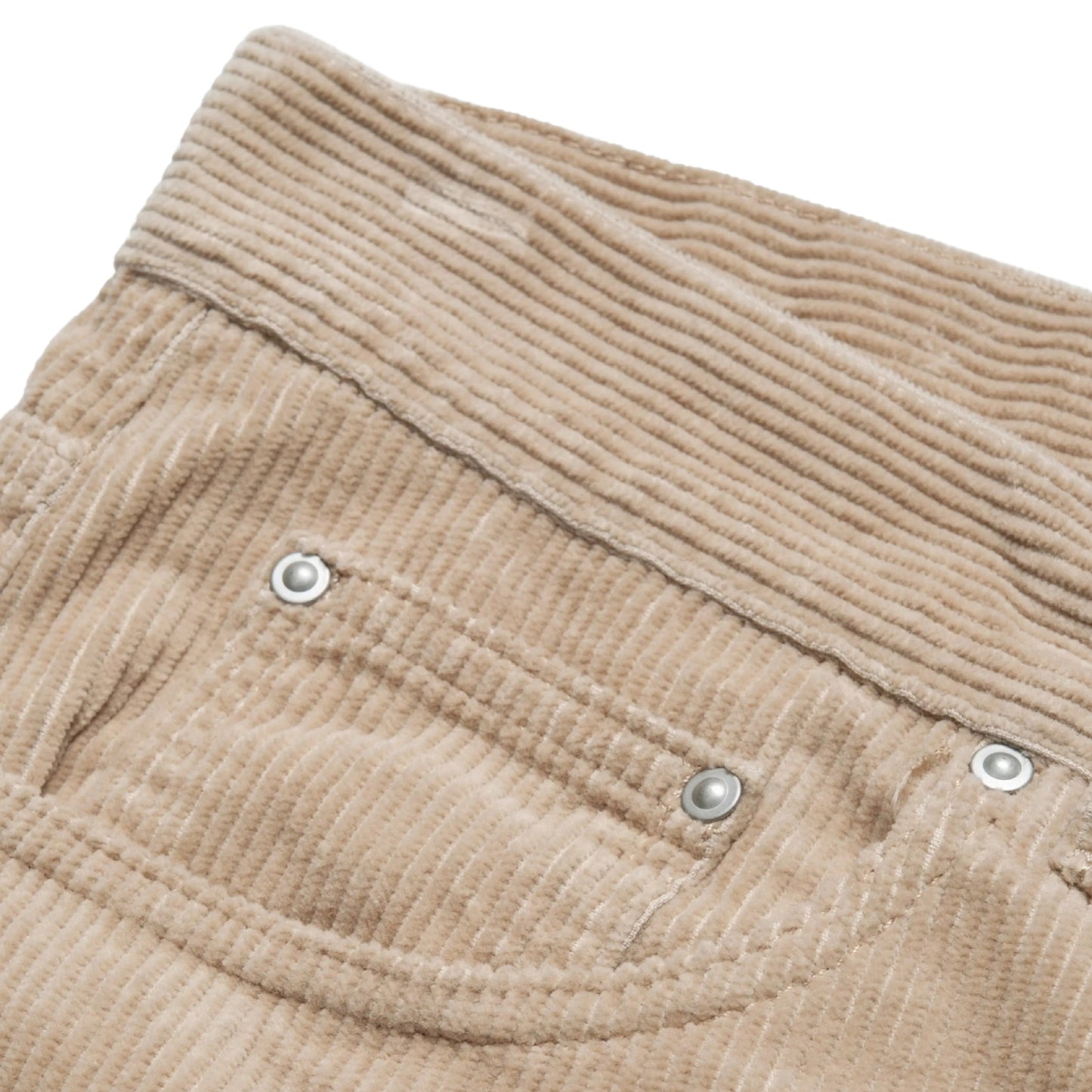 Calças Carhartt WIP Newel Pant em Wall Rinsed — detalhe do bolso frontal esquerdo em close, bombazina Coventry de oito nervuras bege Wall rinsed, abertura do bolso frontal com rebite prateado e micro-bolso com dois rebites prateados visíveis, textura canelada em destaque, fundo branco.