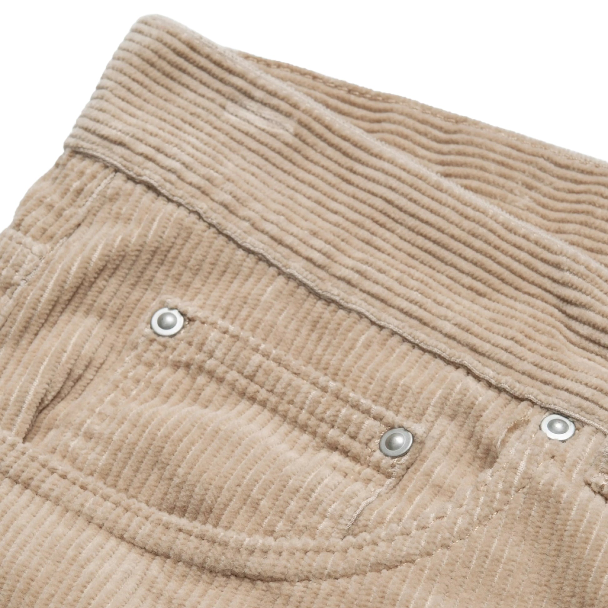 Calças Carhartt WIP Newel Pant em Wall Rinsed — detalhe do bolso frontal esquerdo em close, bombazina Coventry de oito nervuras bege Wall rinsed, abertura do bolso frontal com rebite prateado e micro-bolso com dois rebites prateados visíveis, textura canelada em destaque, fundo branco.