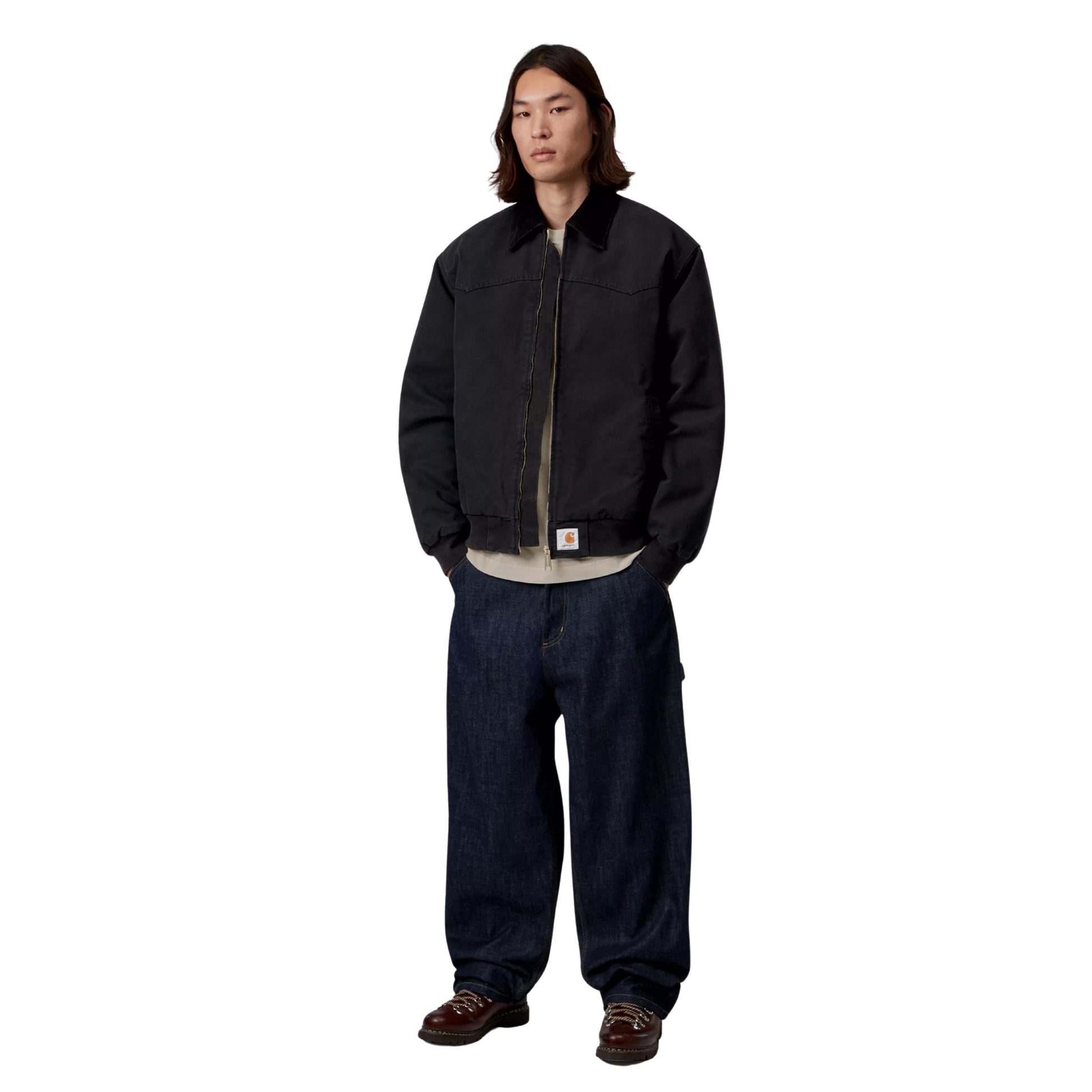 Casaco Carhartt WIP OG Santa Fe em Preto — modelo masculino de corpo inteiro, frente, lona Dearborn preta, fecho dourado, corte Loose OG oversized, sweatshirt bege por baixo, calças cargo denim azul-escuro largas, botas de trabalho bordeaux, fundo branco.