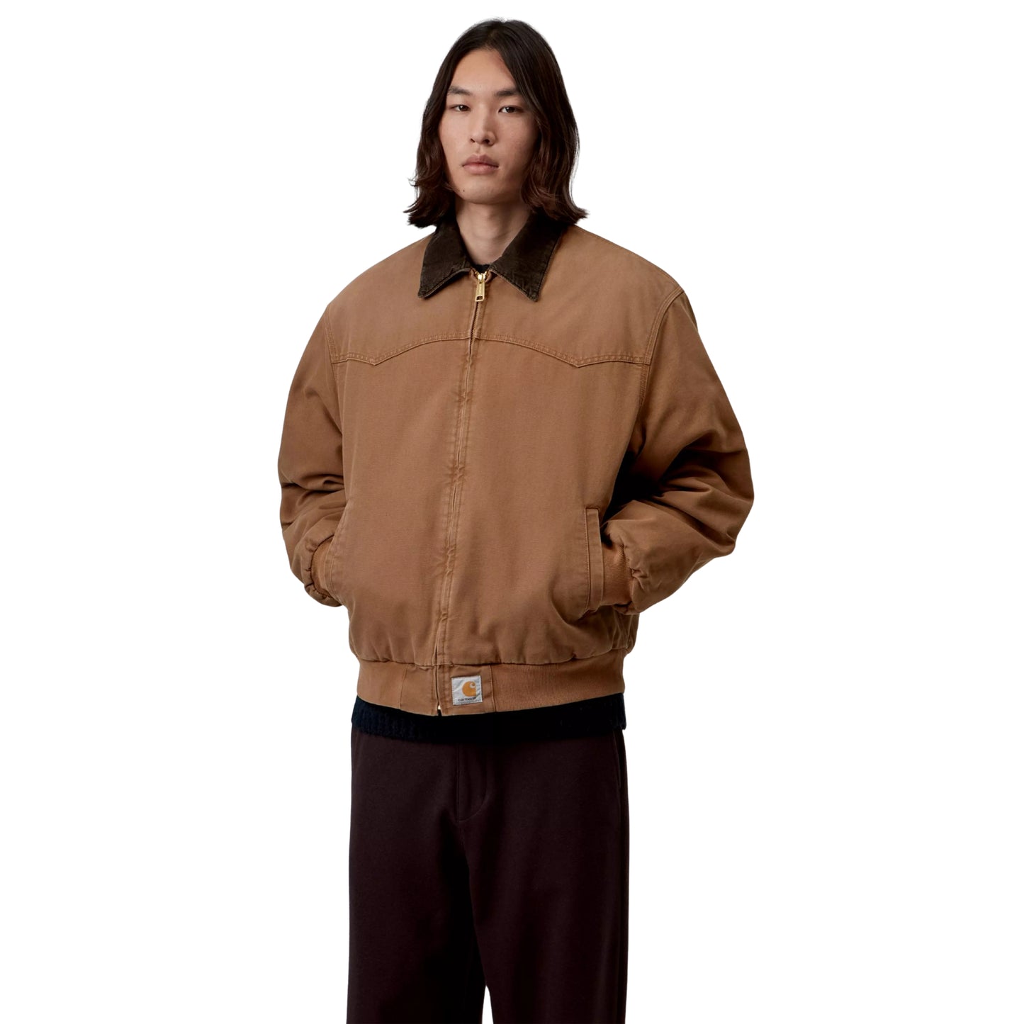 Casaco Carhartt WIP OG Santa Fe em WIP H Brown / Tobacco — modelo masculino de frente, meio corpo, fecho de correr dourado fechado, gola bombazine castanho-escuro, costuras em arco no peito, Square Label Carhartt WIP na bainha, mãos nos bolsos, calças wide-leg bordeaux-escuro, fundo branco.