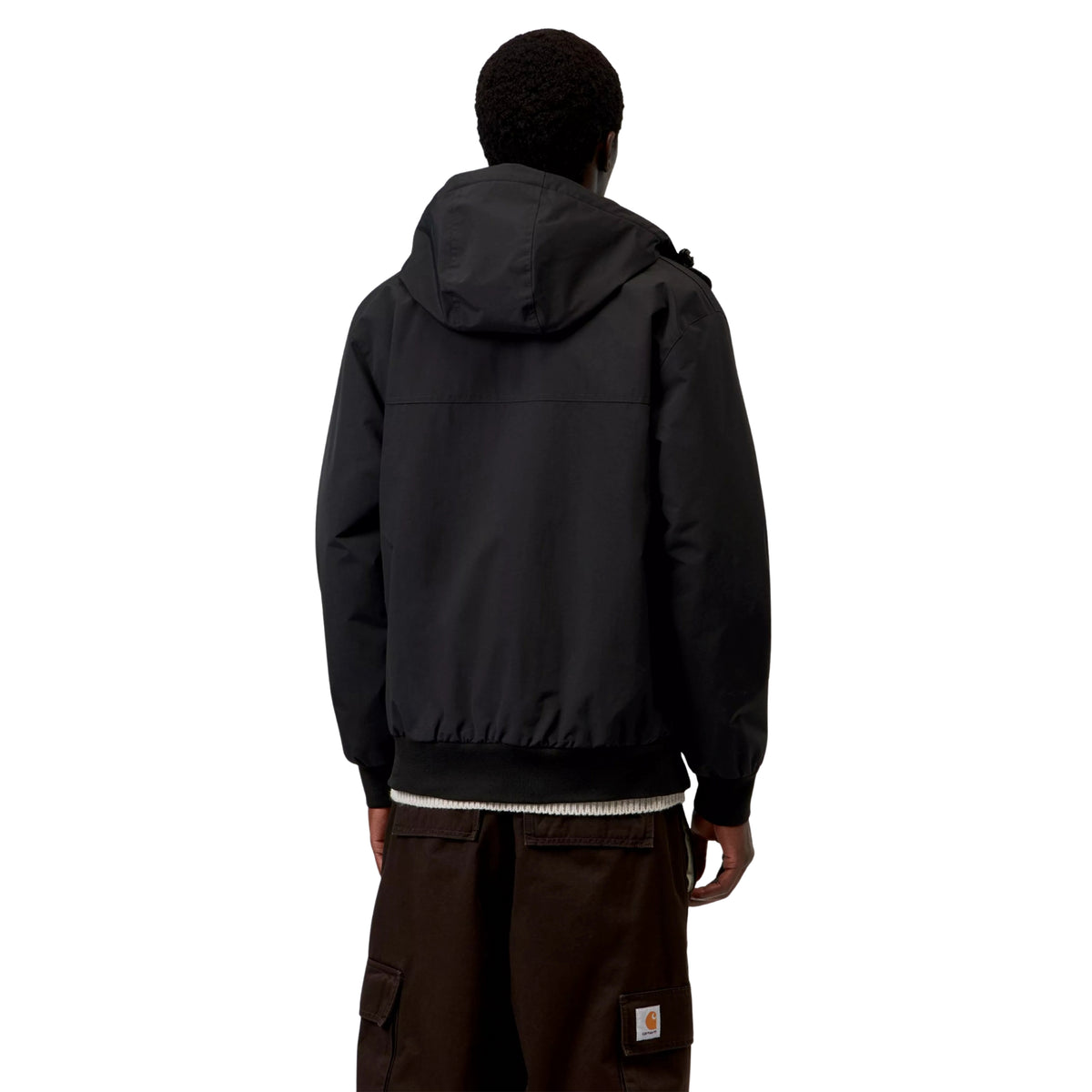 Casaco com carapuço Carhartt WIP Hooded Sail em Preto/Branco, vista de costas a três quartos no modelo, mostrando o carapuço descido, a costura horizontal nas costas e os punhos e bainha canelados.