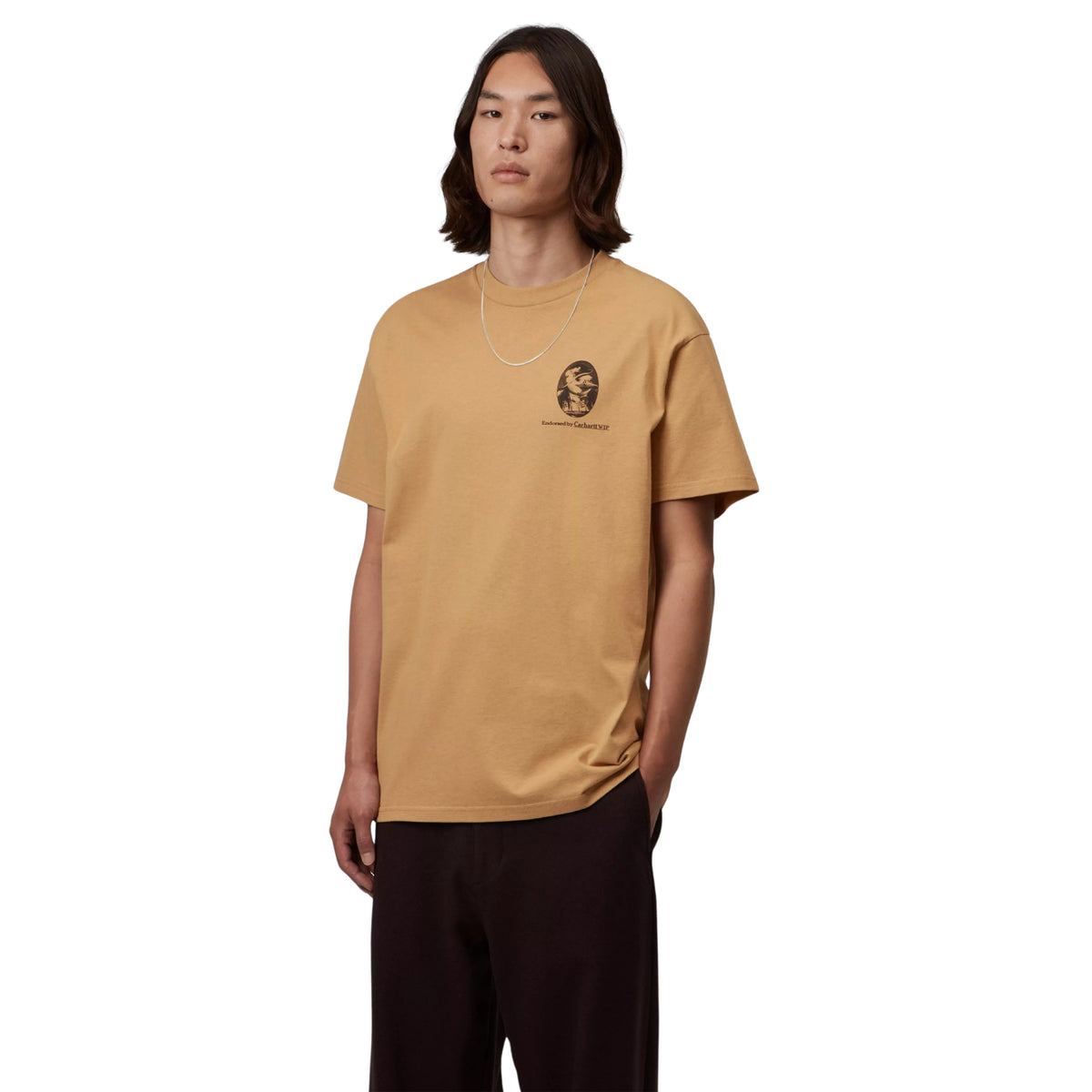 T-shirt de manga curta Carhartt WIP S/S Vote em WIP Dusty H — modelo masculino de frente, corpo inteiro, gráfico The Mayor em miniatura no peito esquerdo com texto Endorsed by Carhartt WIP, decote redondo, loose fit, calças largas pretas, fundo branco.