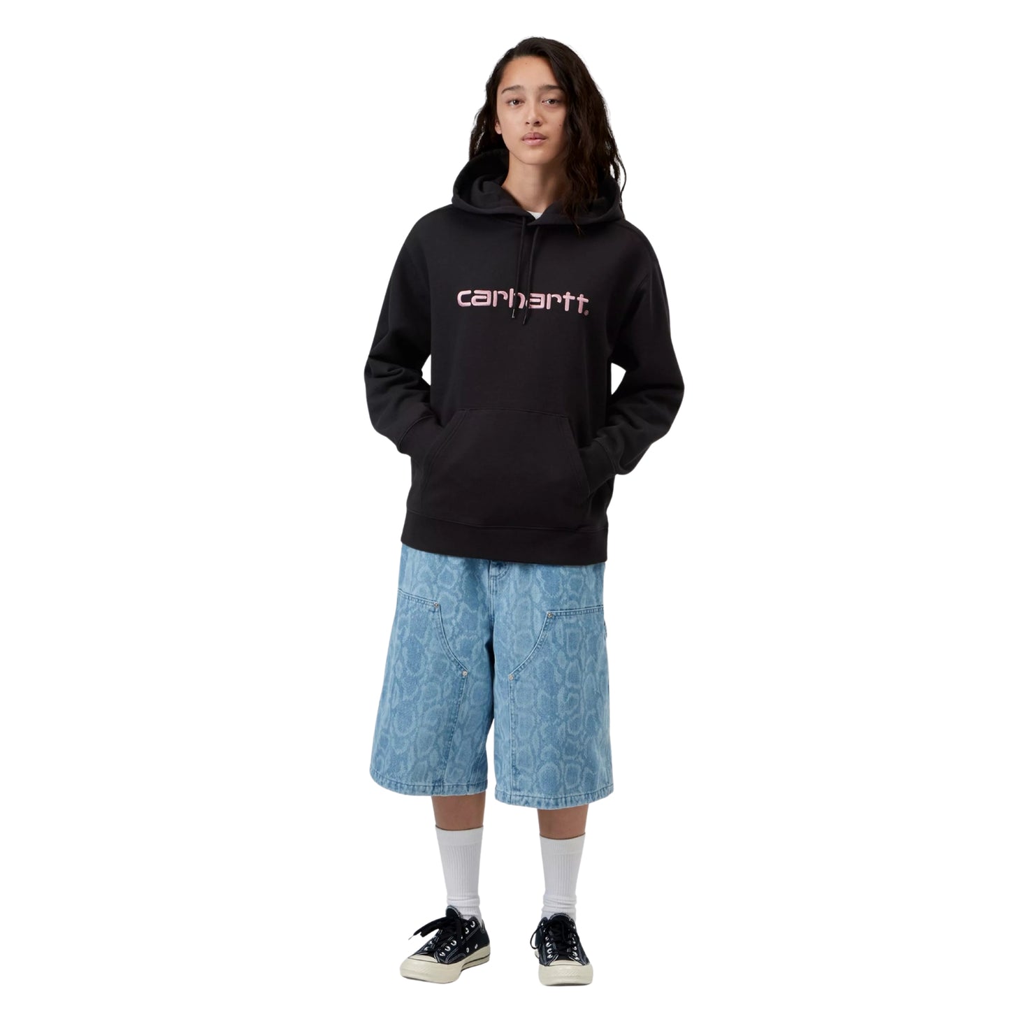 Sweat com carapuço para mulher Carhartt WIP W' Hooded Carhartt Sweatshirt em Black / Hortensia — look completo com modelo, corpo inteiro, corte regular, mãos no bolso canguru, combinado com calças largas de ganga Carhartt WIP, meias brancas e sapatilhas Converse pretas.