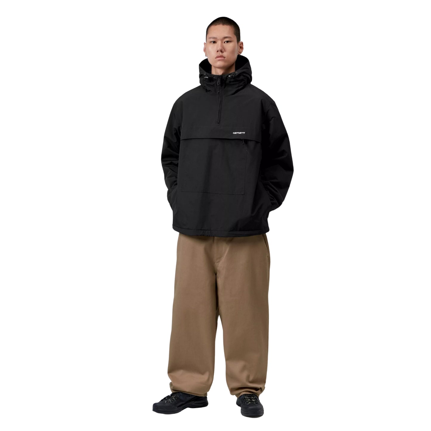 Anorak Carhartt WIP Windbreaker Pullover em Black / White — modelo masculino de frente, corpo inteiro, logótipo Script "carhartt." bordado em White, calças wide-leg bege Carhartt WIP, sapatilhas pretas, nylon Supplex® preto Black, fundo branco