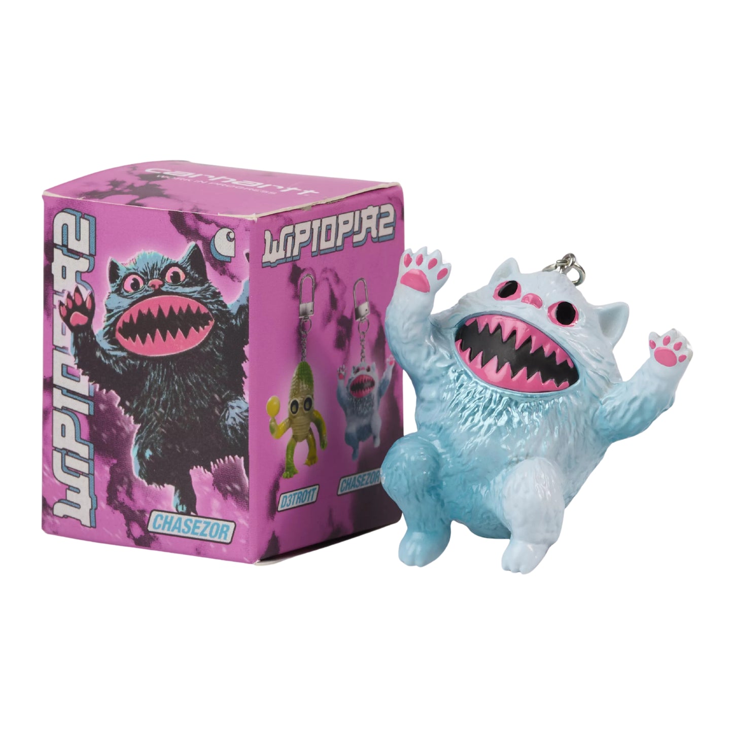 Porta-chaves Carhartt WIP Wiptopia II Chasezor — figura felina em PVC azul-gelo pintada à mão com pelo texturado, olhos cor-de-rosa, boca aberta com dentes afiados e patas cor-de-rosa, argola metálica no topo, ao lado da caixa colecionável rosa com ilustração "Wiptopia 2" e nome "Chasezor", fundo branco.