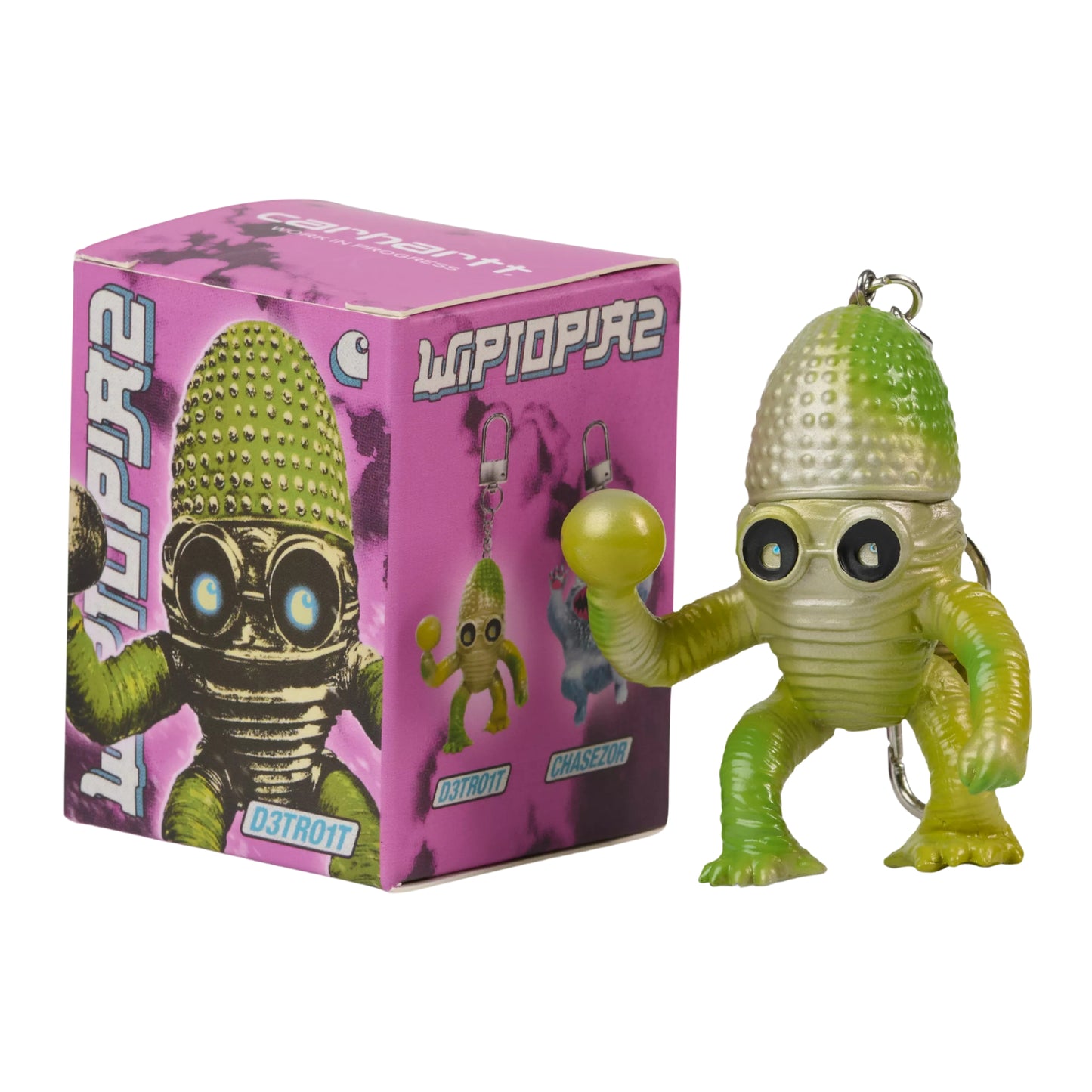 Porta-chaves Carhartt WIP Wiptopia II D3tro1t — figura alienígena em PVC verde-amarelado pintada à mão com cabeça cónica texturada, olhos grandes redondos e corpo musculado com gradiente verde, argola metálica no topo, ao lado da caixa colecionável rosa com ilustração "Wiptopia 2" e nome "D3tro1t", fundo branco.