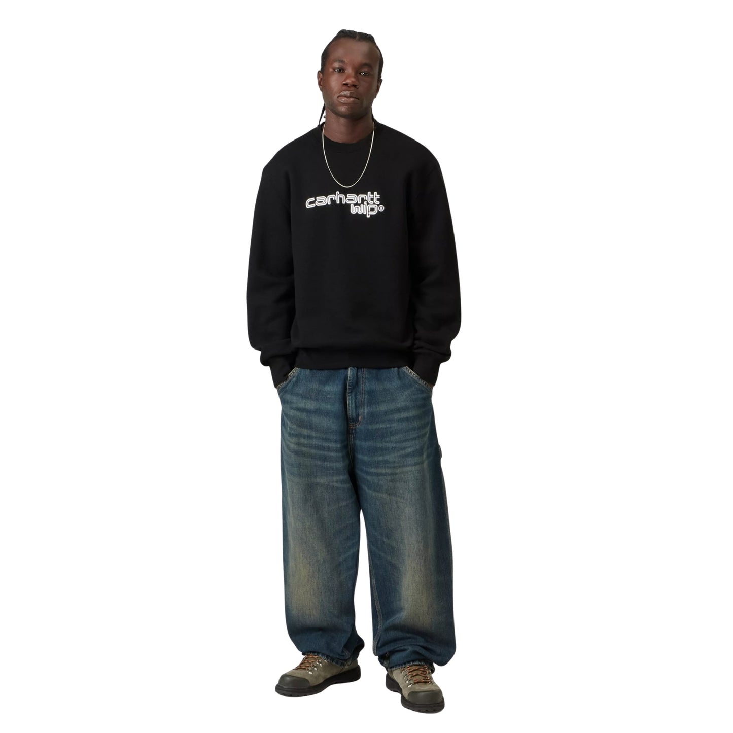 Camisola Carhartt WIP Wireless Sweat em Black / Wax — modelo masculino de frente, corpo inteiro, cabelo comprido castanho, fio fino ao pescoço, bordado "carhartt wip®" em branco/Wax visível ao peito, calças wide-leg escuras, sapatilhas chunky pretas, malha de algodão escovada preta, fundo branco.